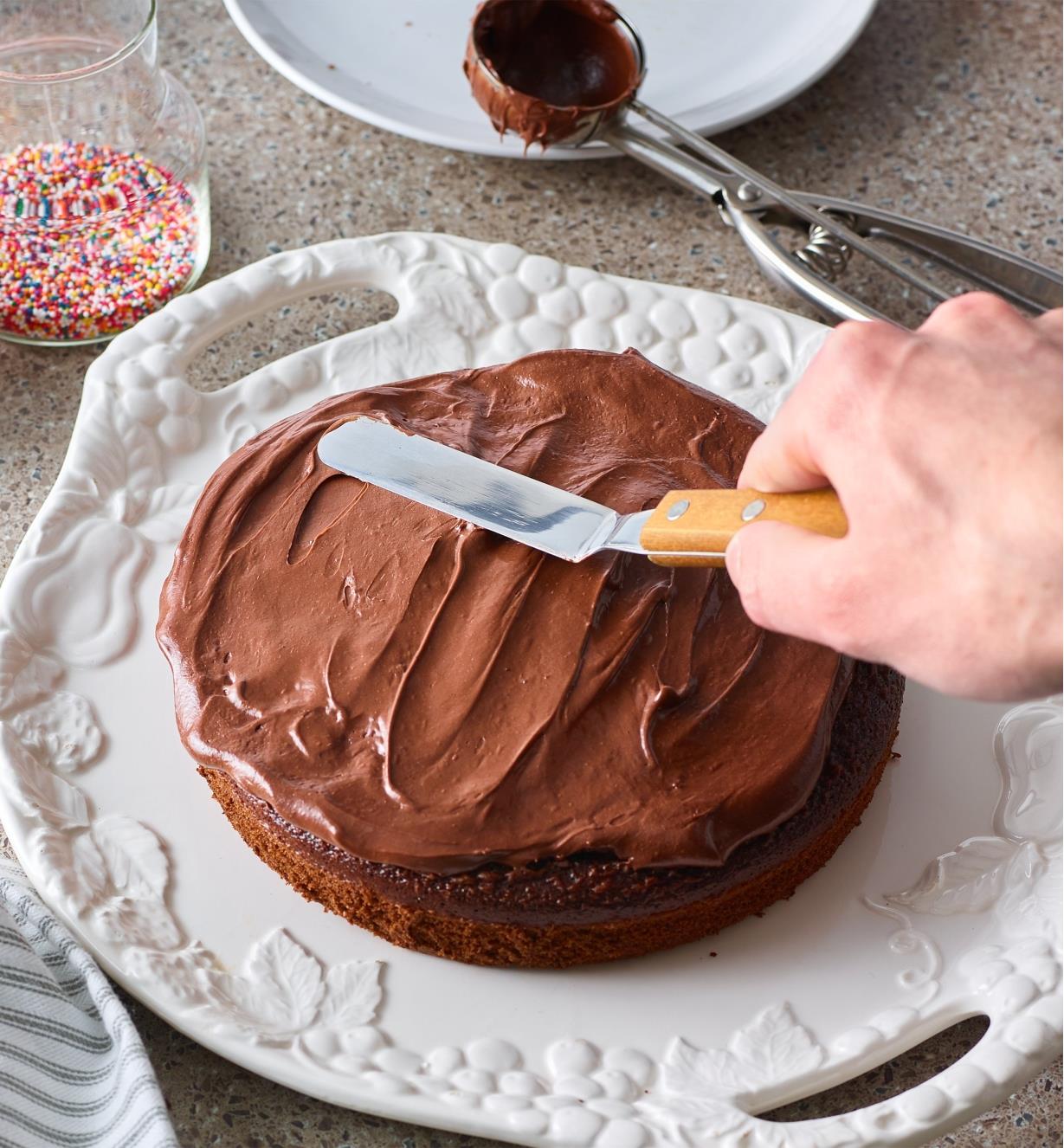 Personne appliquant du glaçage sur un gâteau avec une spatule à pâtisserie coudée