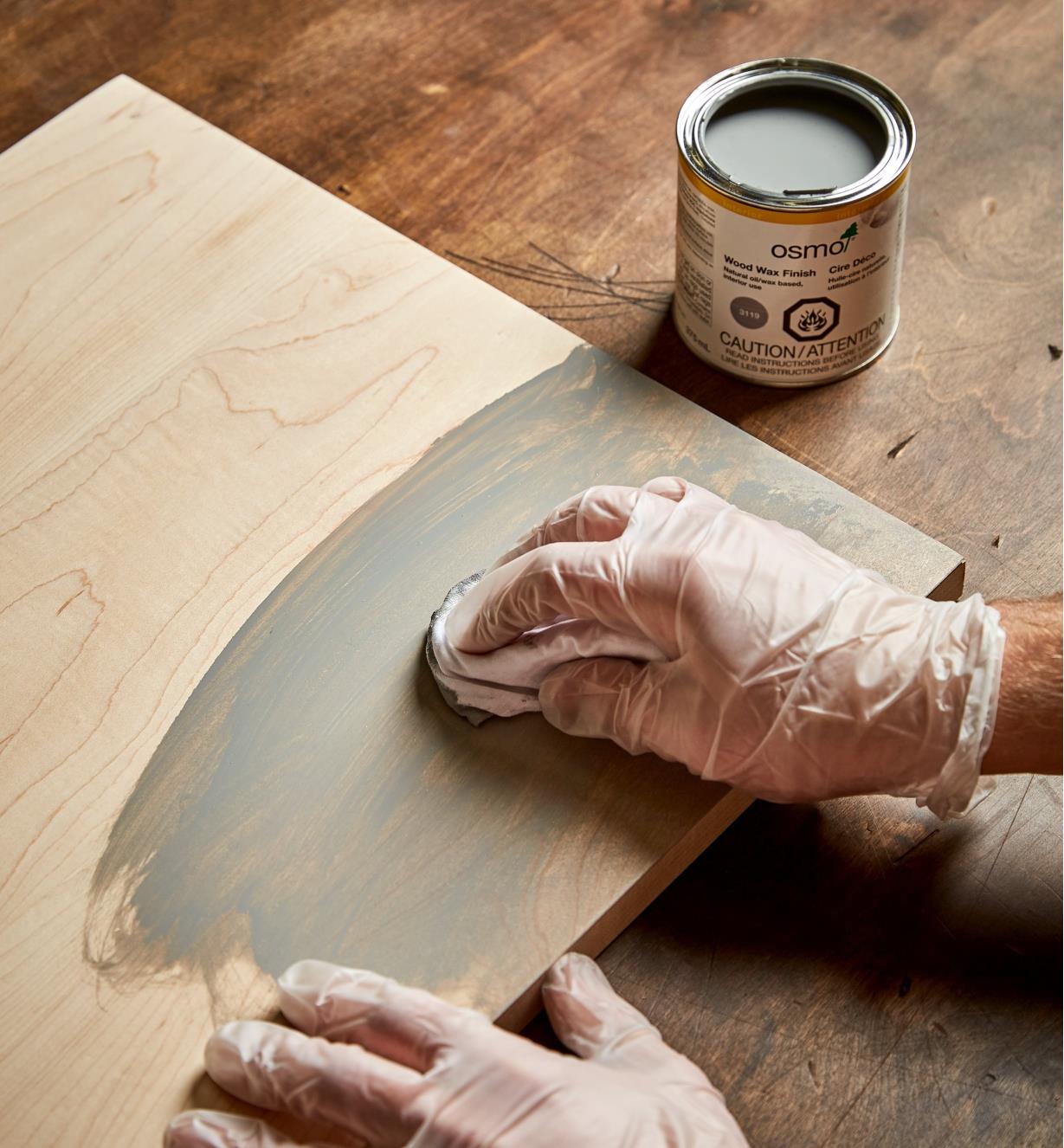 Using a cloth to apply Osmo silk gray wood wax to a wood surface