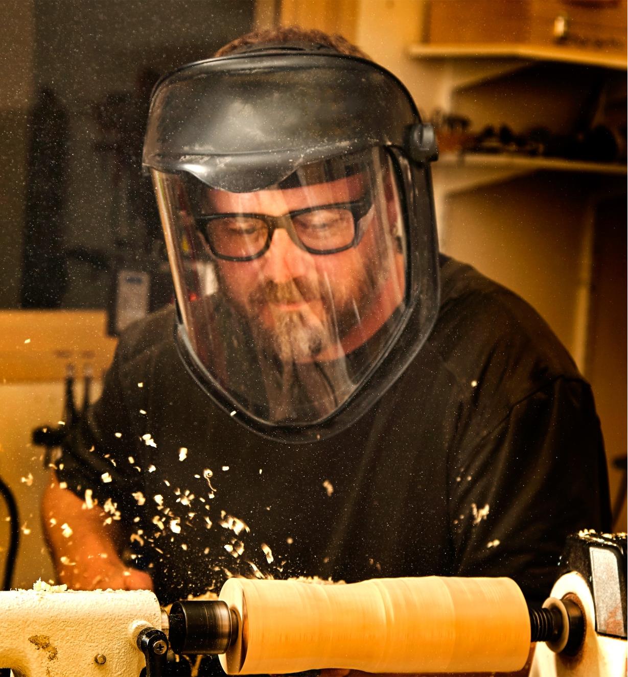 A man wears a Professional Face Shield while turning on a lathe