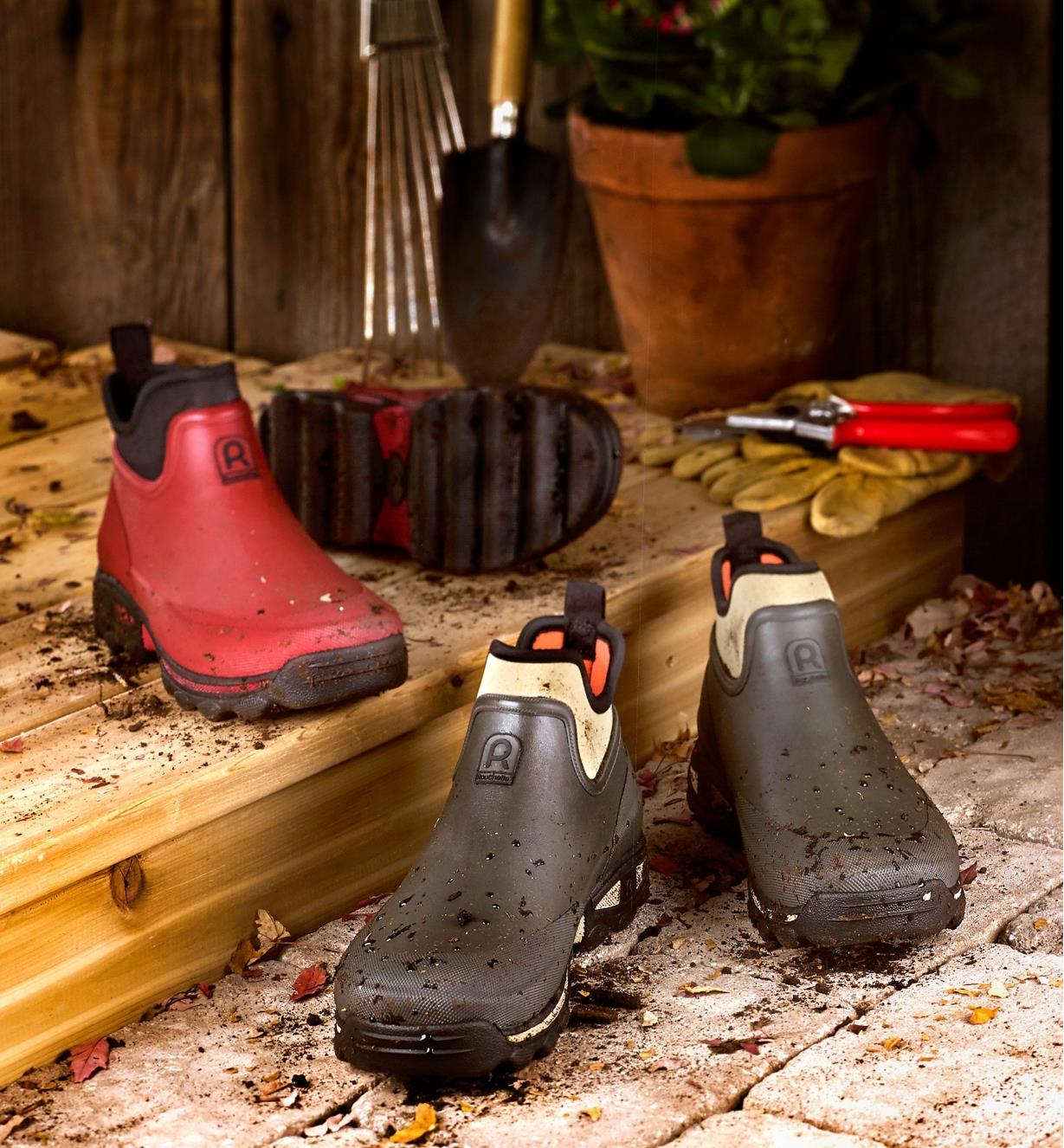 Pair of red and pair of green Gardener's Shoes sitting on a doorstep with garden tools and gloves.