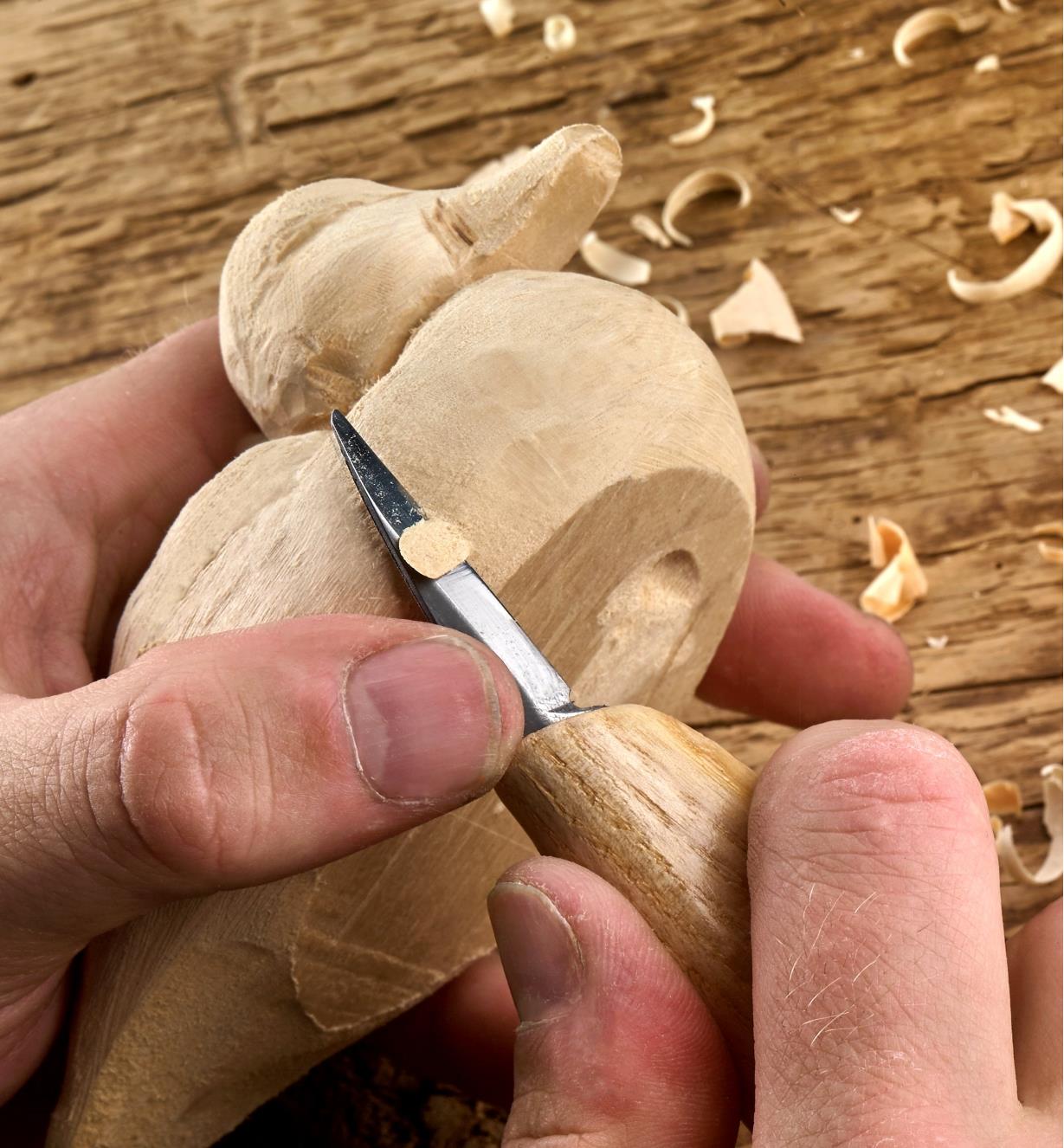 A carver uses a Flexcut fine-point knife to carve a small wooden duck