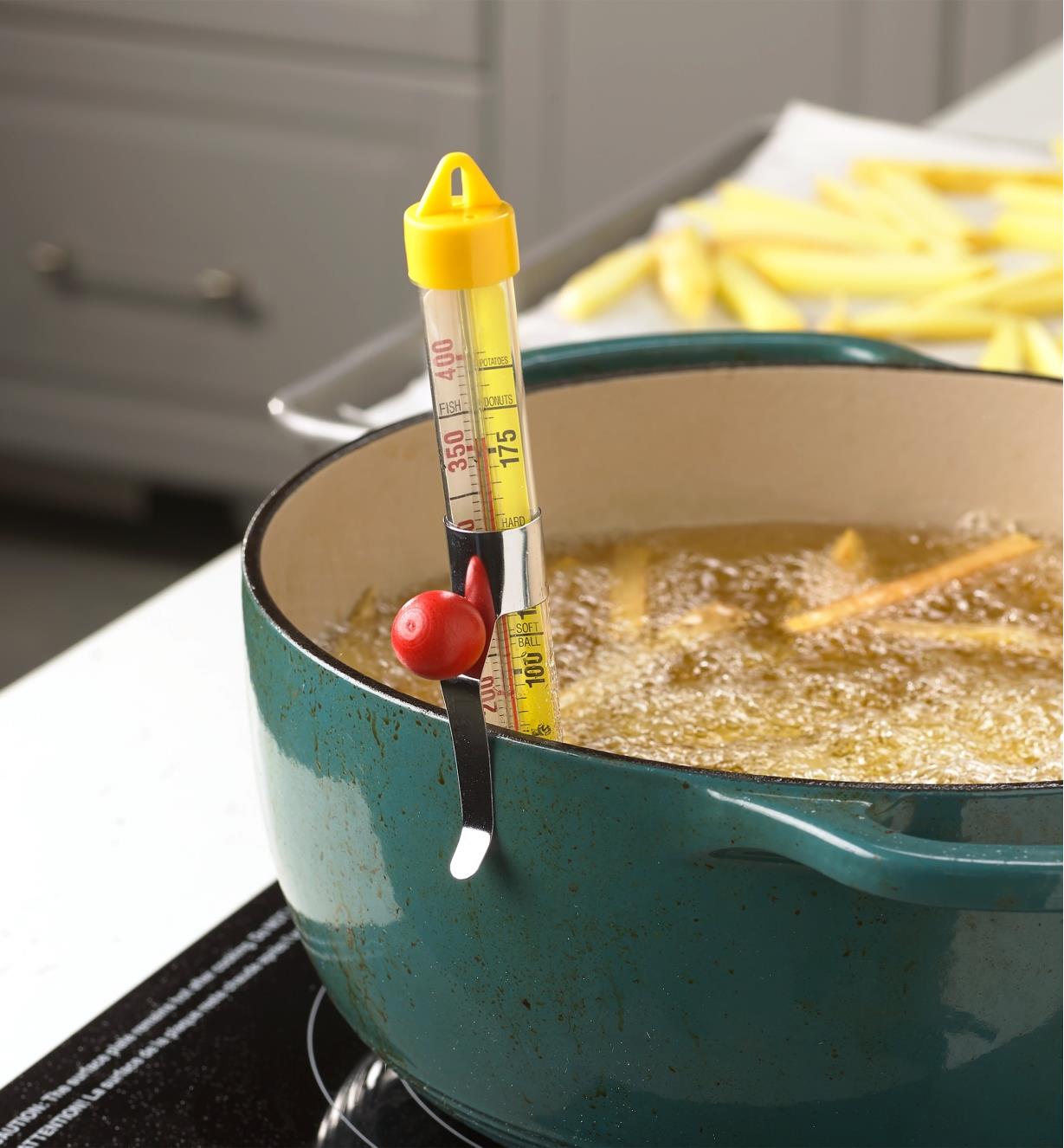 The candy and deep-fry thermometer clipped to a pot of deep-frying potato strips