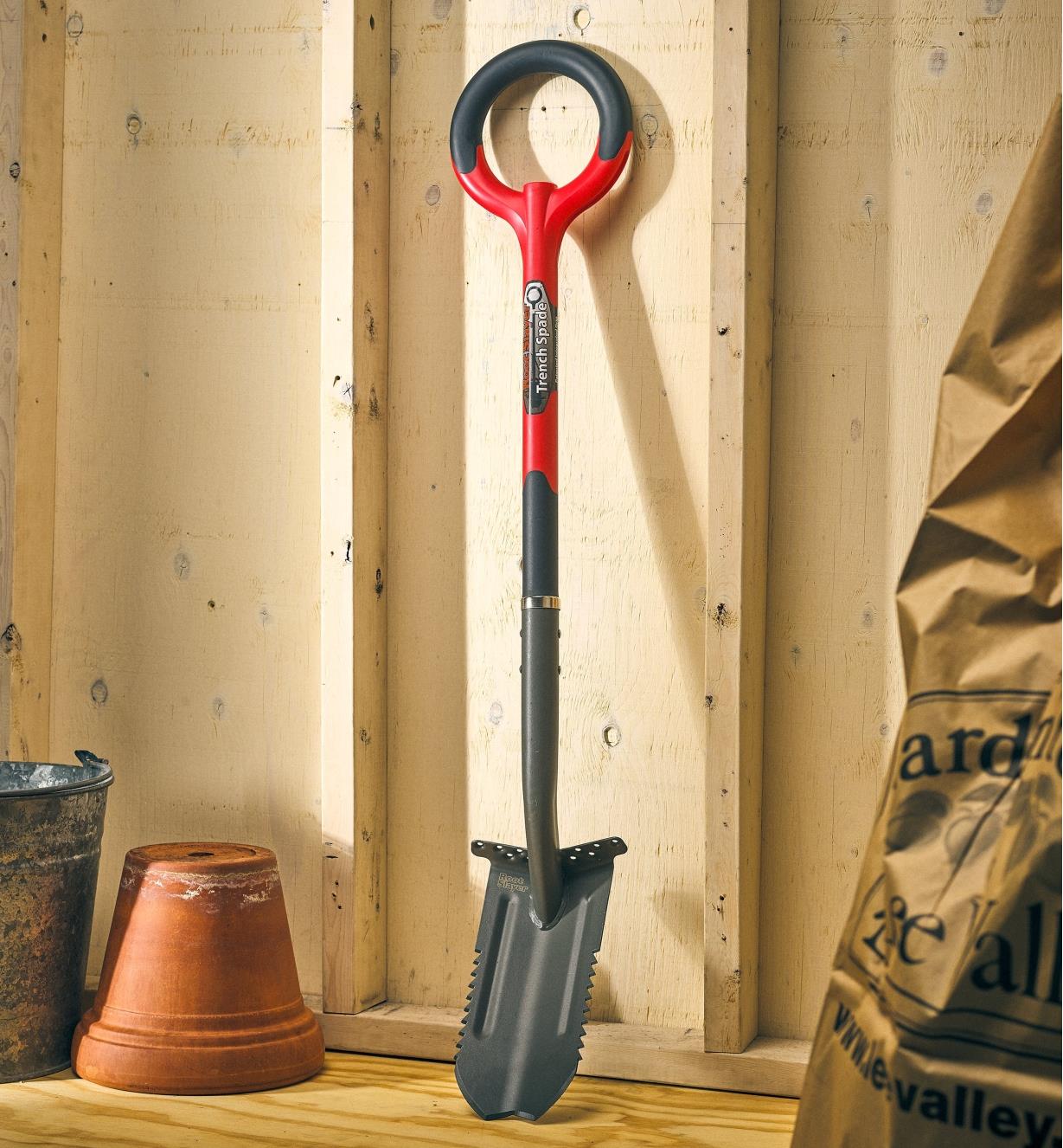 A Radius root cutter trenching spade leaning against the wall of a garden shed.