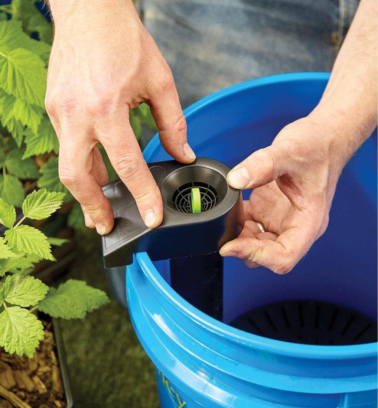 Clipping a bracket with a green tab in its center to the top of the bucket