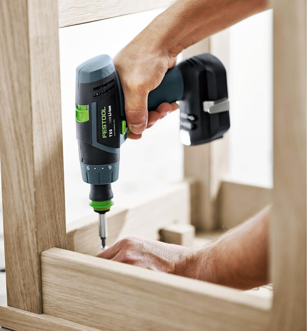 Driving a screw into the underside of a chair with TXS Cordless Drill