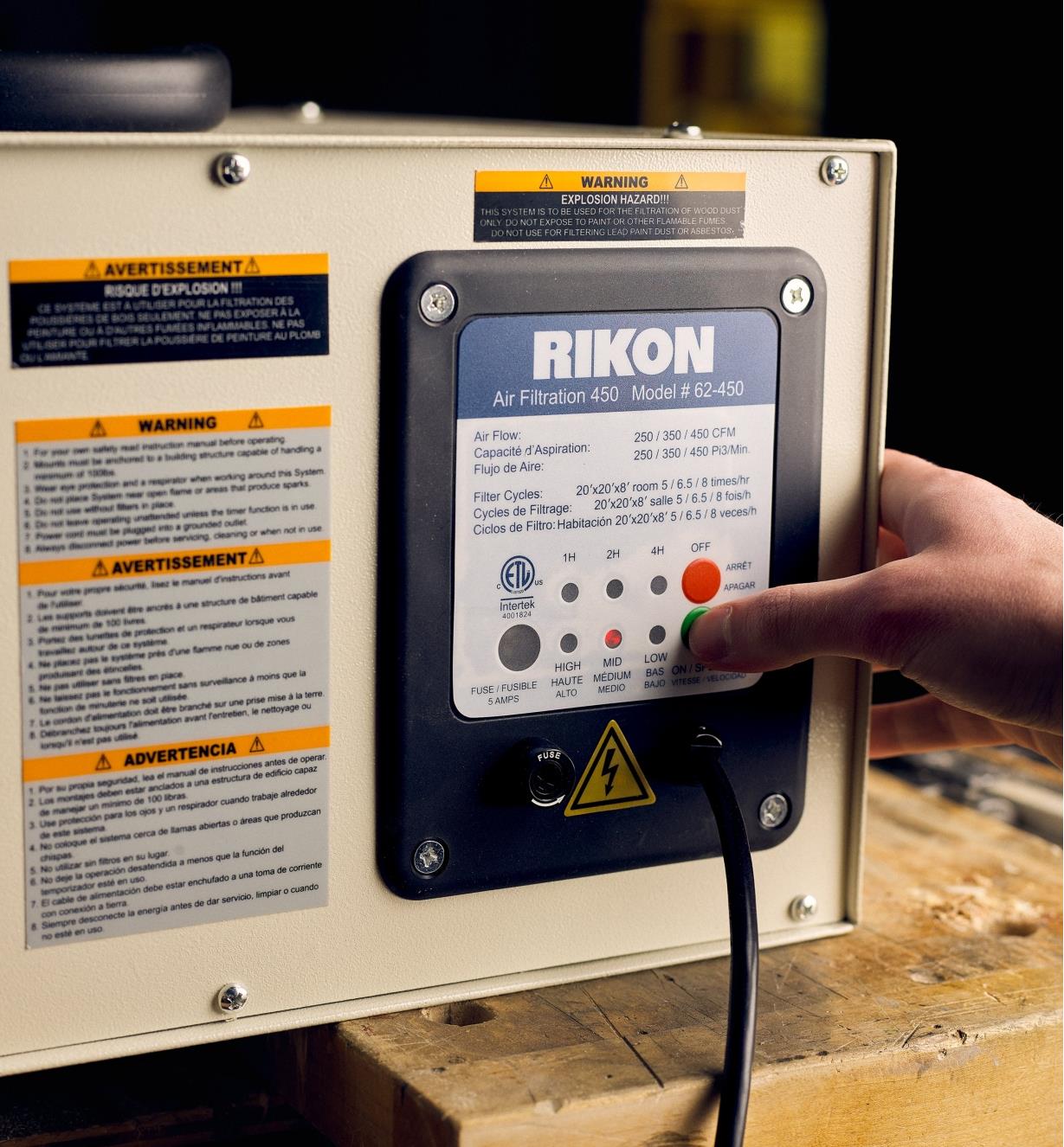 Pressing a button on the side of a Rikon 450 cfm air cleaner