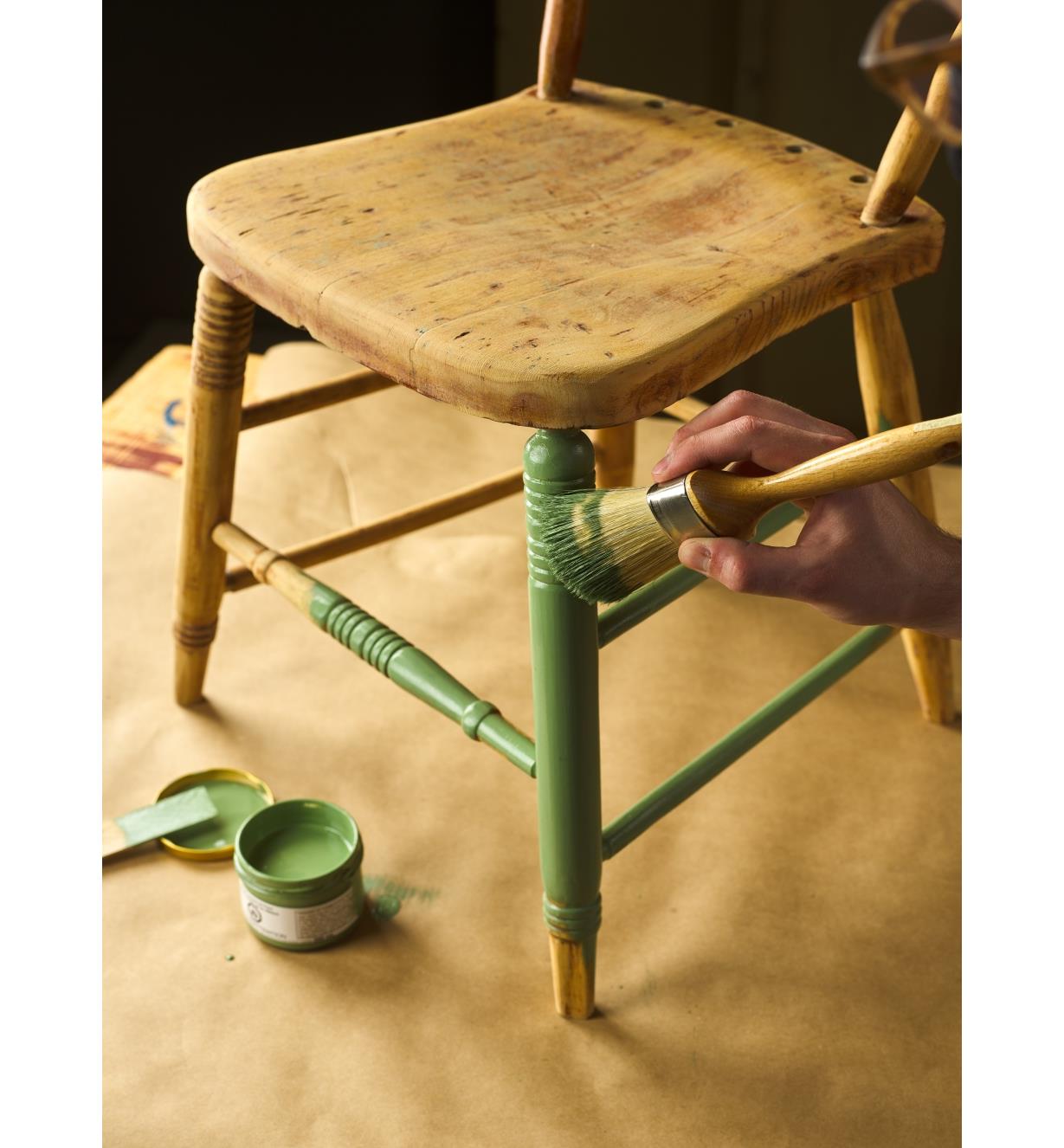 Using a brush to apply Allback linseed oil paint to a wooden chair