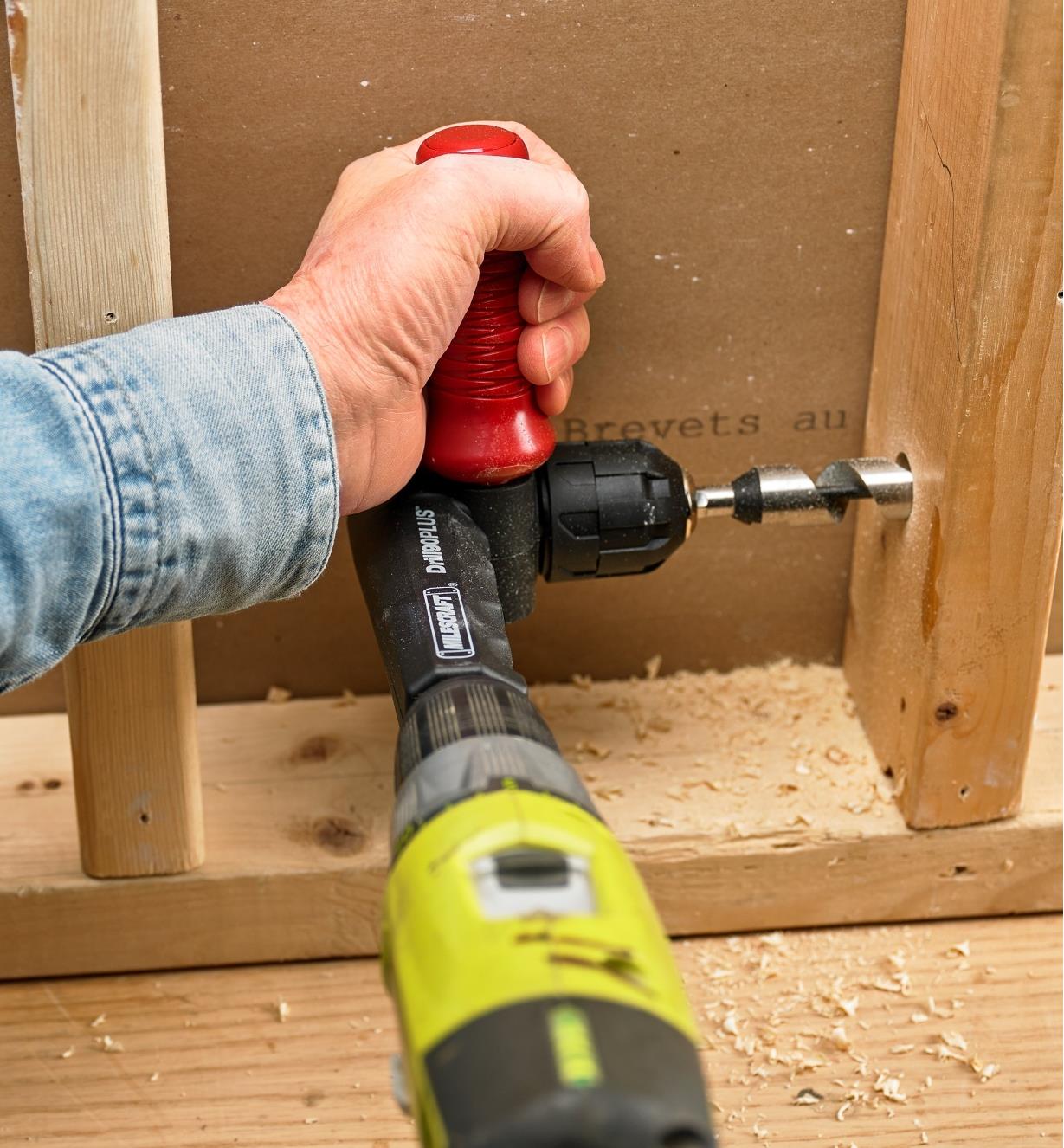 Boring a hole in a wall stud using the 90° drilling attachment on a standard drill