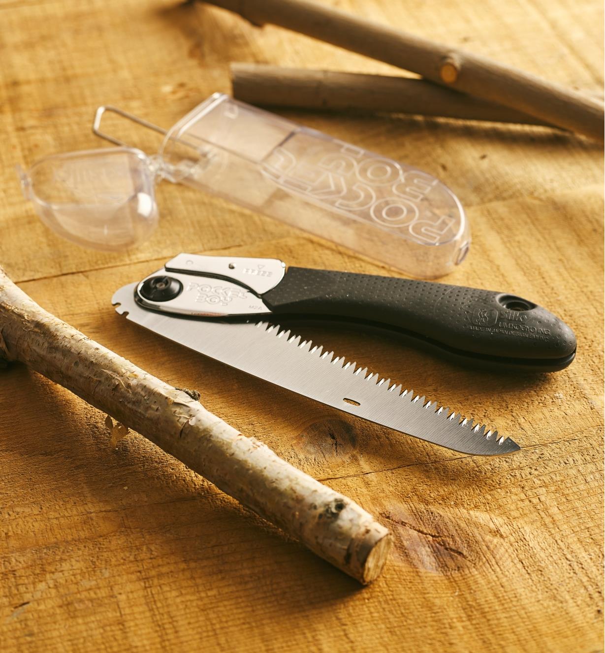 A folded Silky Pocketboy 170M folding saw and storage case shown with pruned branches