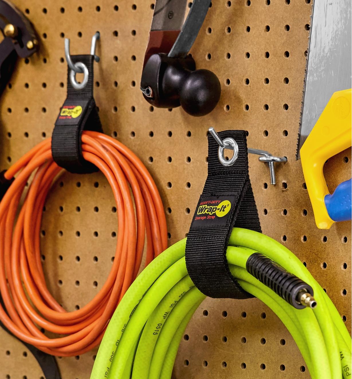 Heavy-duty storage wraps used to hang a pneumatic hose and an extension cord on a pegboard wall