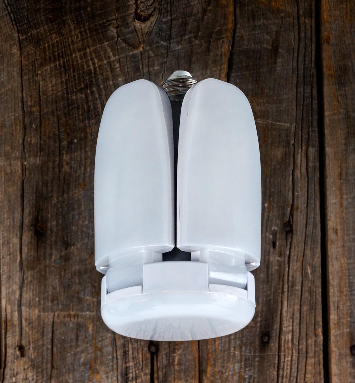 A directional LED ceiling light with its arms fully raised to cast light far out to the sides