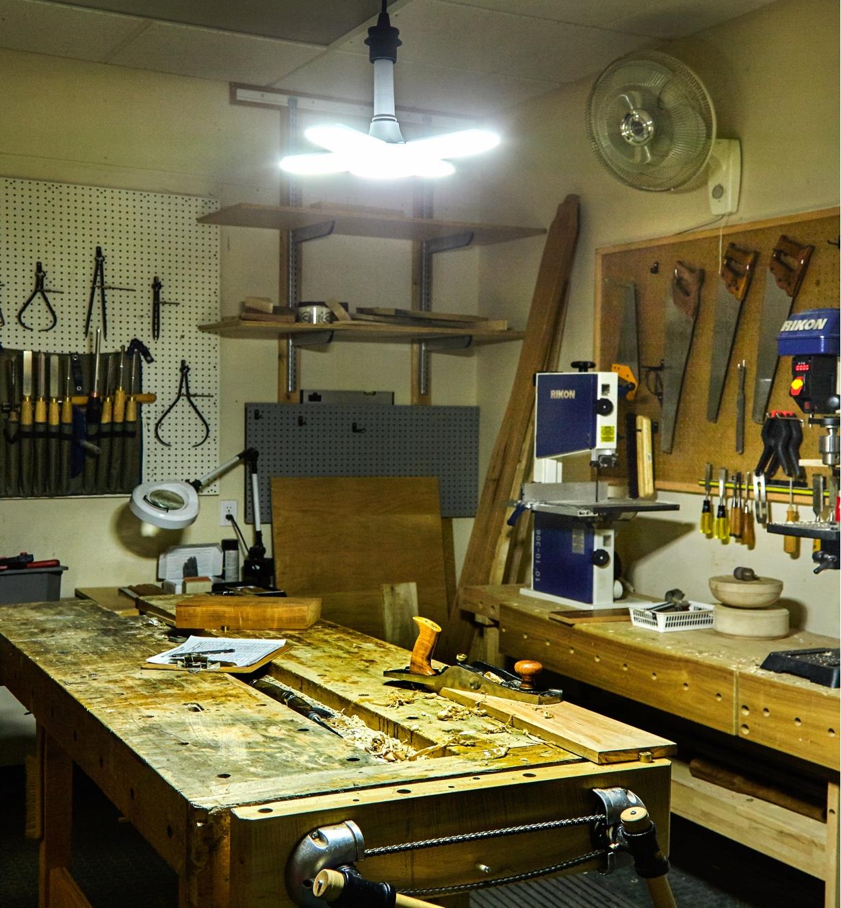 A directional LED ceiling light installed over a workbench to illuminate a workshop