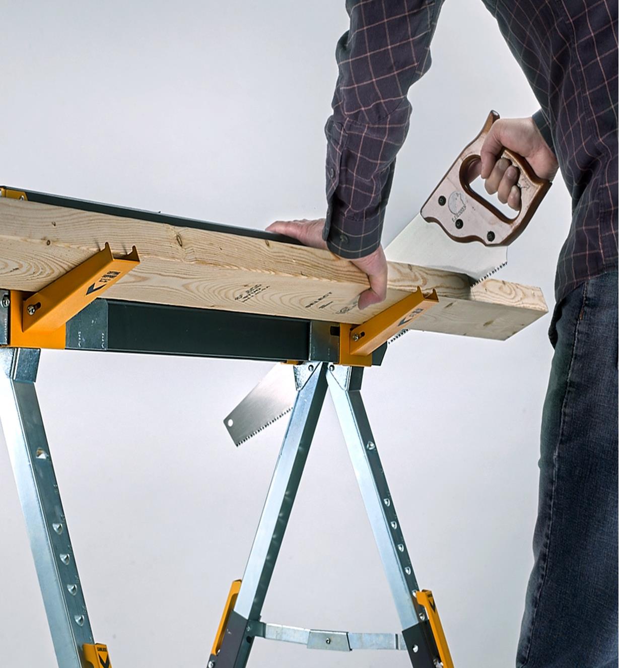 Using a handsaw to cut lumber held horizontally on the fold-out brackets of a C700 sawhorse