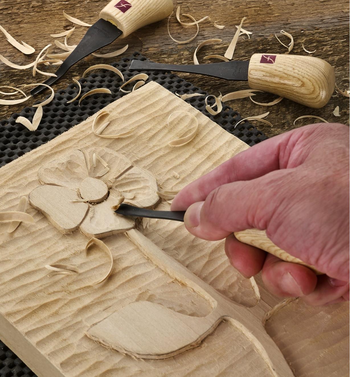 A carver uses a gouge from the palm-carving set to work on a low-relief panel carving