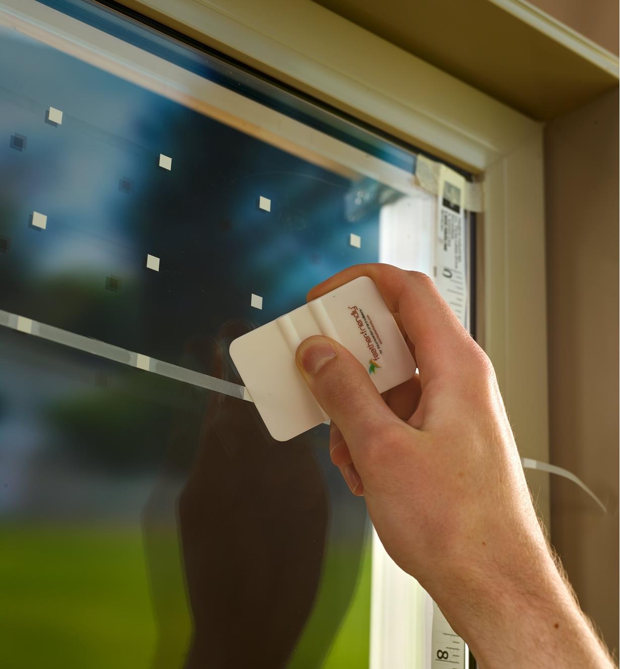 Pressing a line of tape against a window with a plastic card