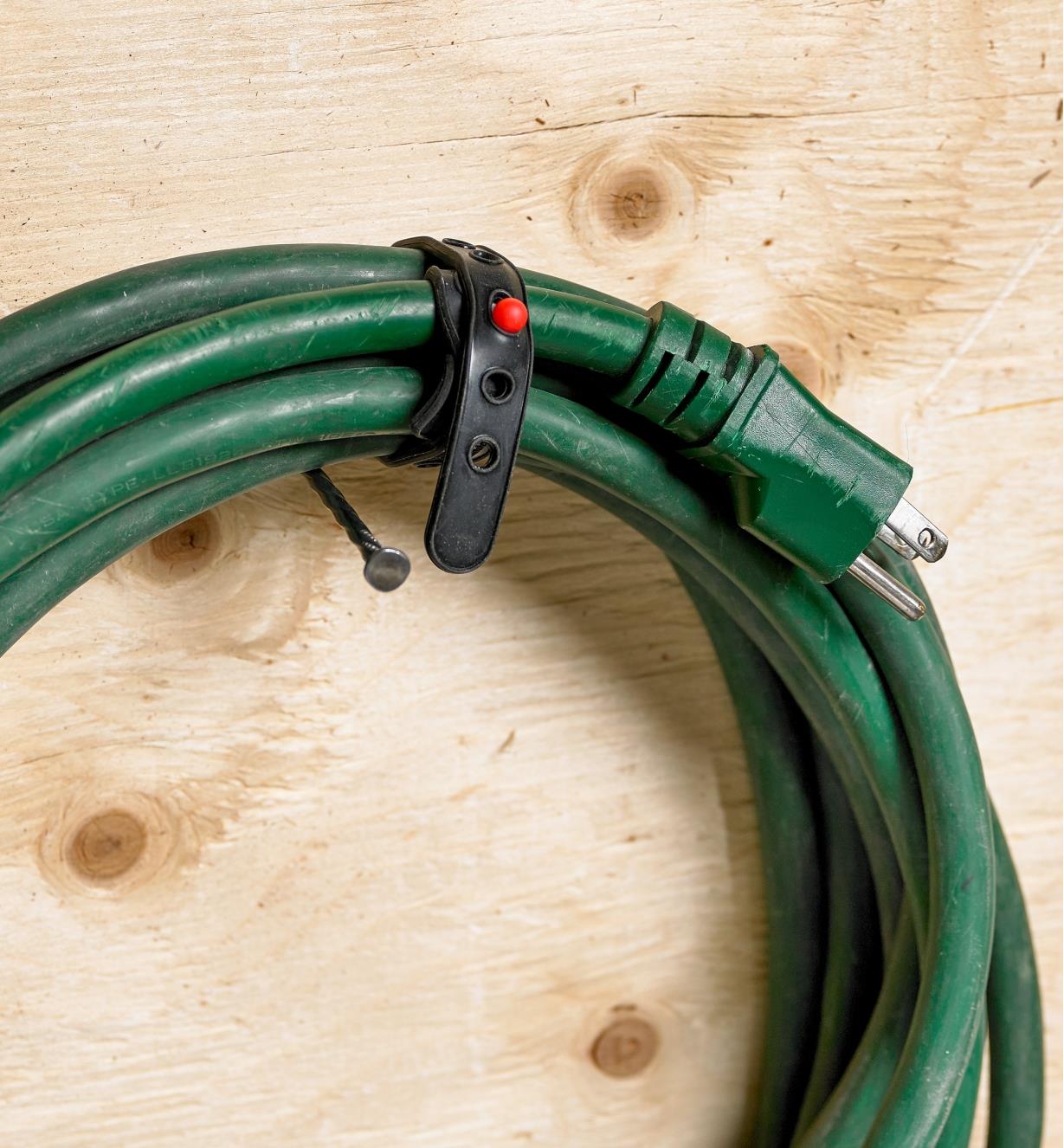 A coiled extension cord secured with a Wrap-N-Strap hanging on a wall