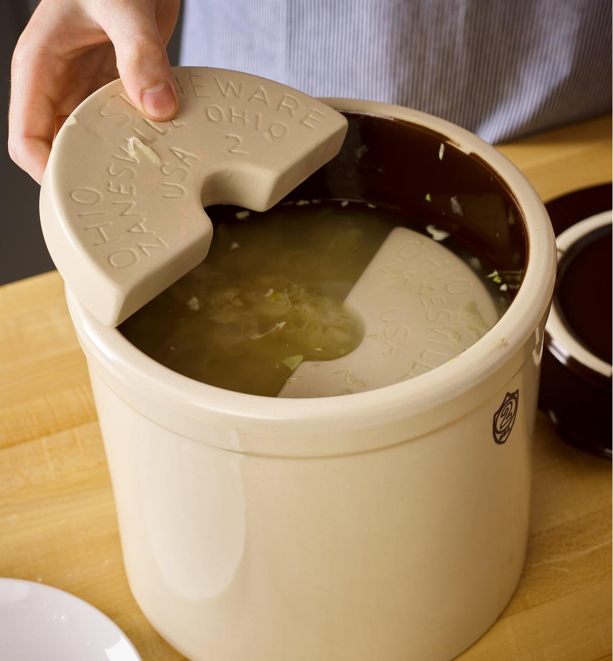 Placing weights on top of ingredients in the fermentation crock