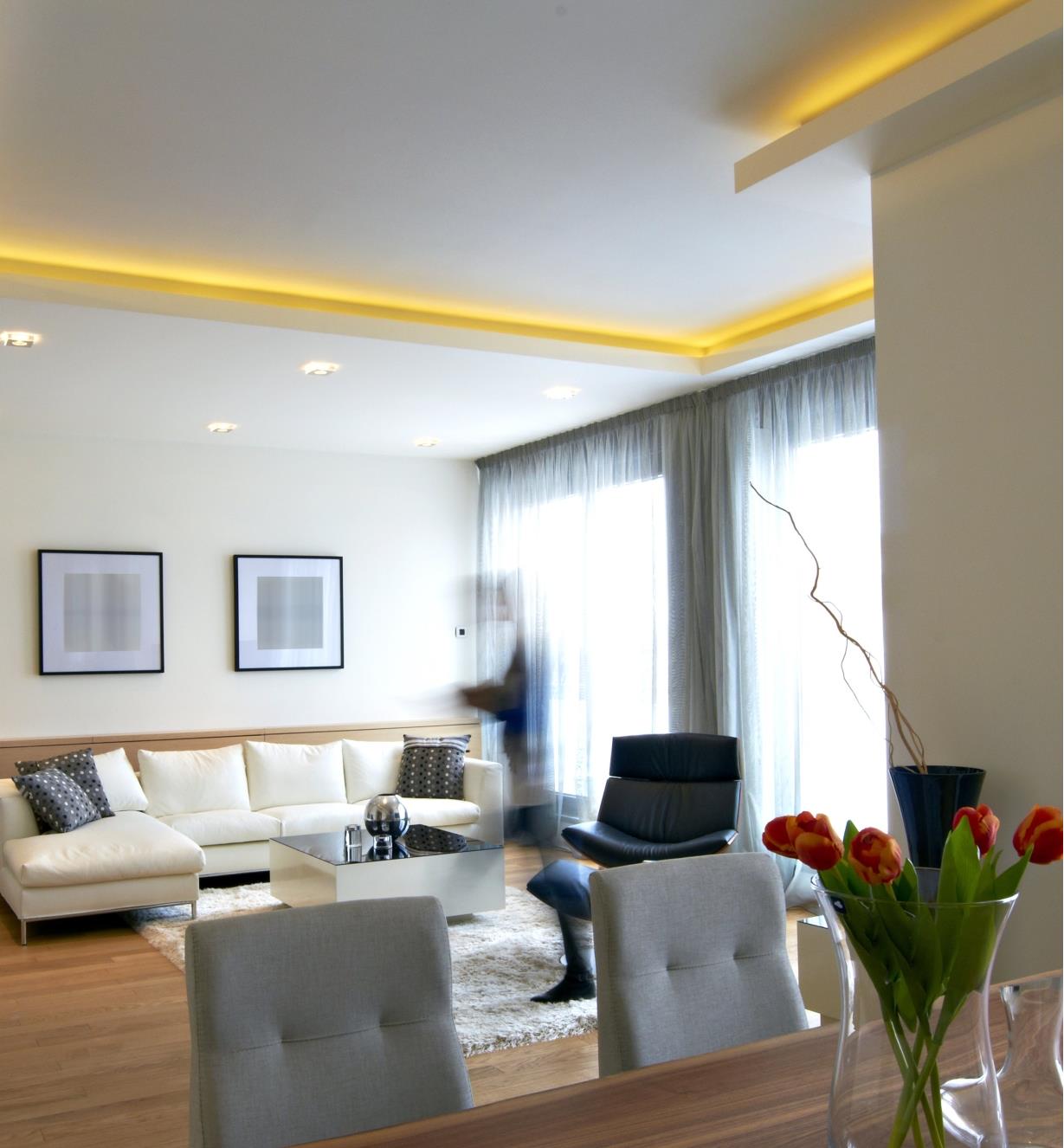 A living room with an inset ceiling illuminated by indirect lighting along its edges
