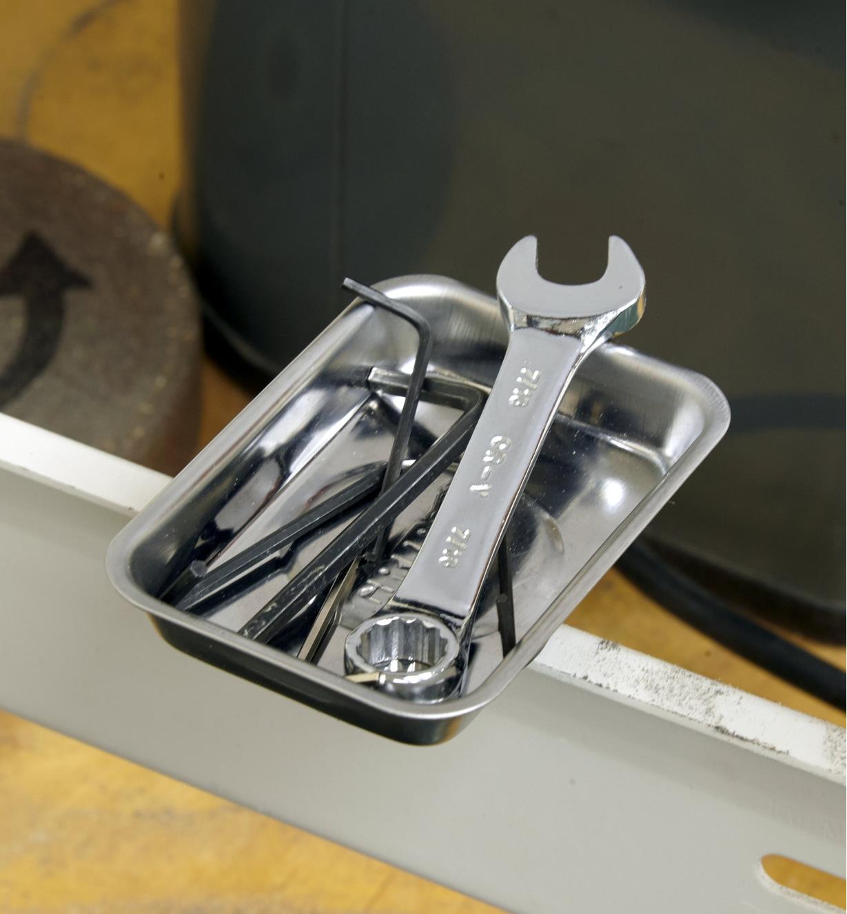 Small wrenches in a mini magnetic parts tray held to a metal frame