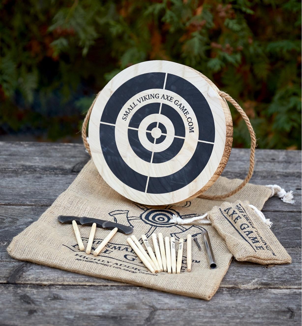 The contents of the mini axe-throwing game arranged on a backyard deck