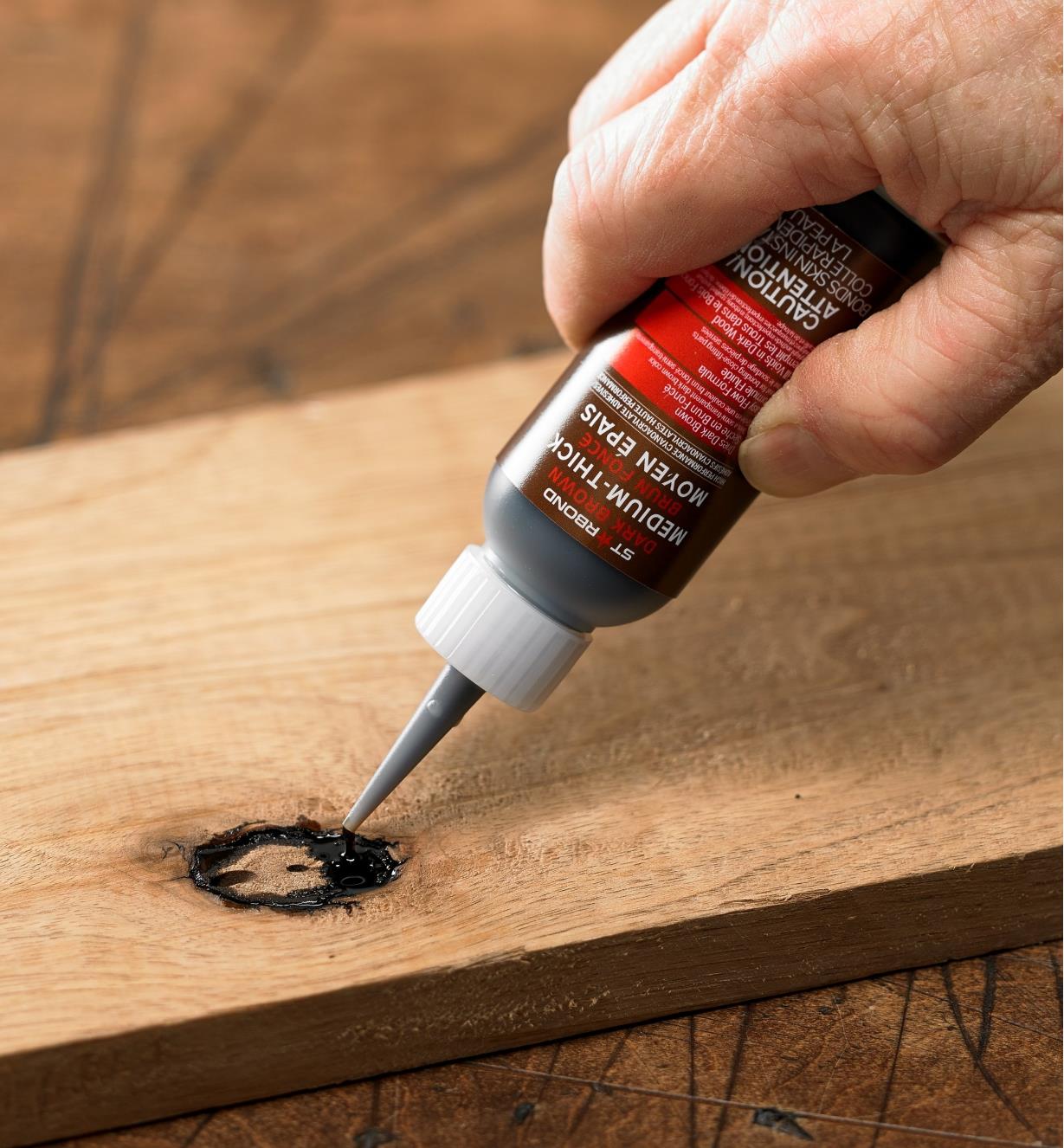 Applying Starbond dark brown CA glue to a knot in wood