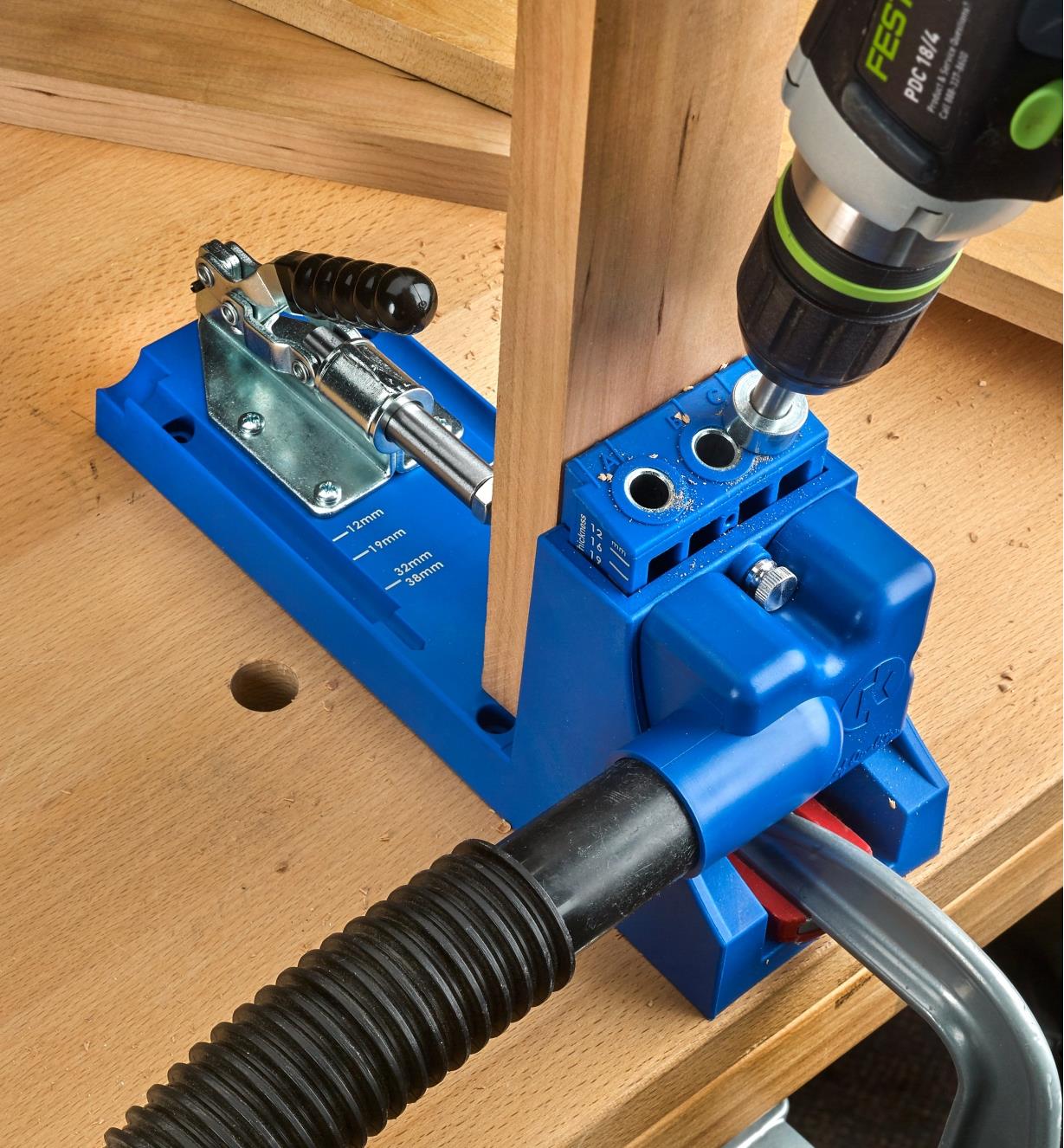 A K4 metric jig on a benchtop, connected to a vacuum hose, used to drill pocket holes for joinery