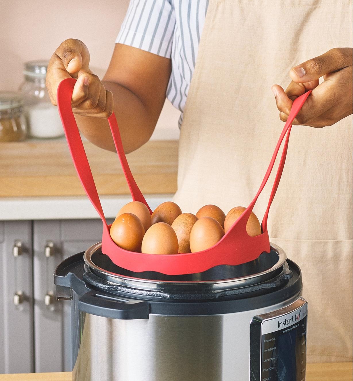 Eggs in a silicone pressure cooker sling are lowered into a multi-cooker