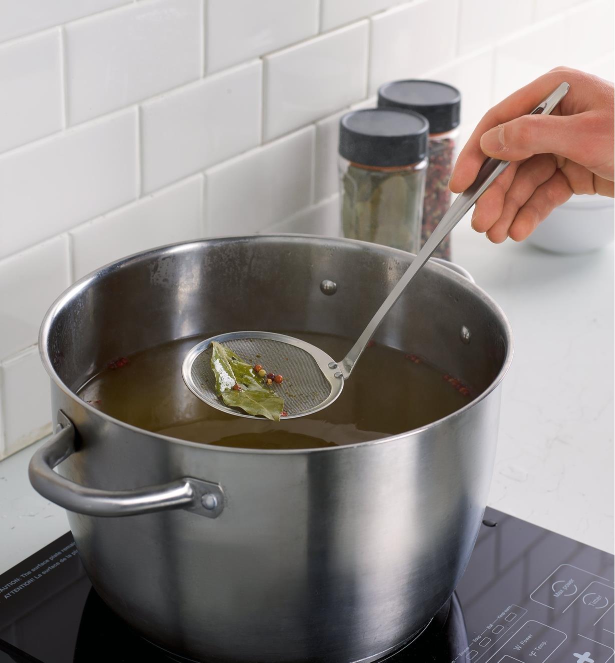 Removing spices from broth using the fine-mesh skimming ladle