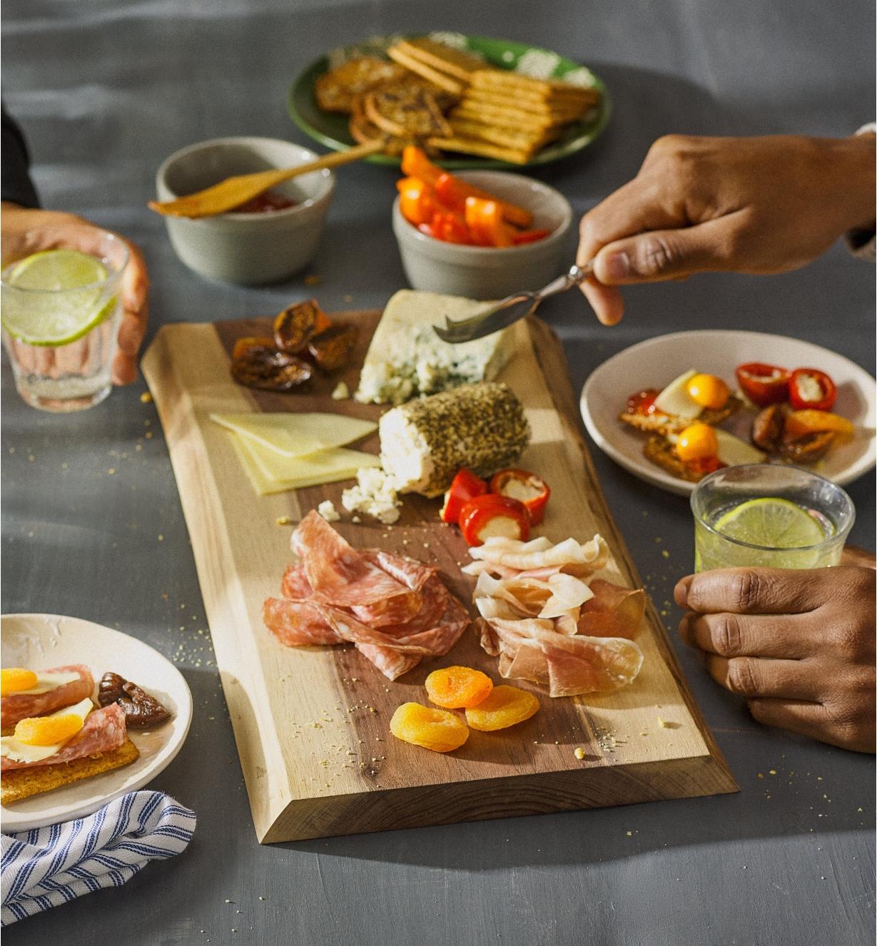 Two people sharing a variety of cheese, cured meats, nuts and fruit arranged on the charcuterie board