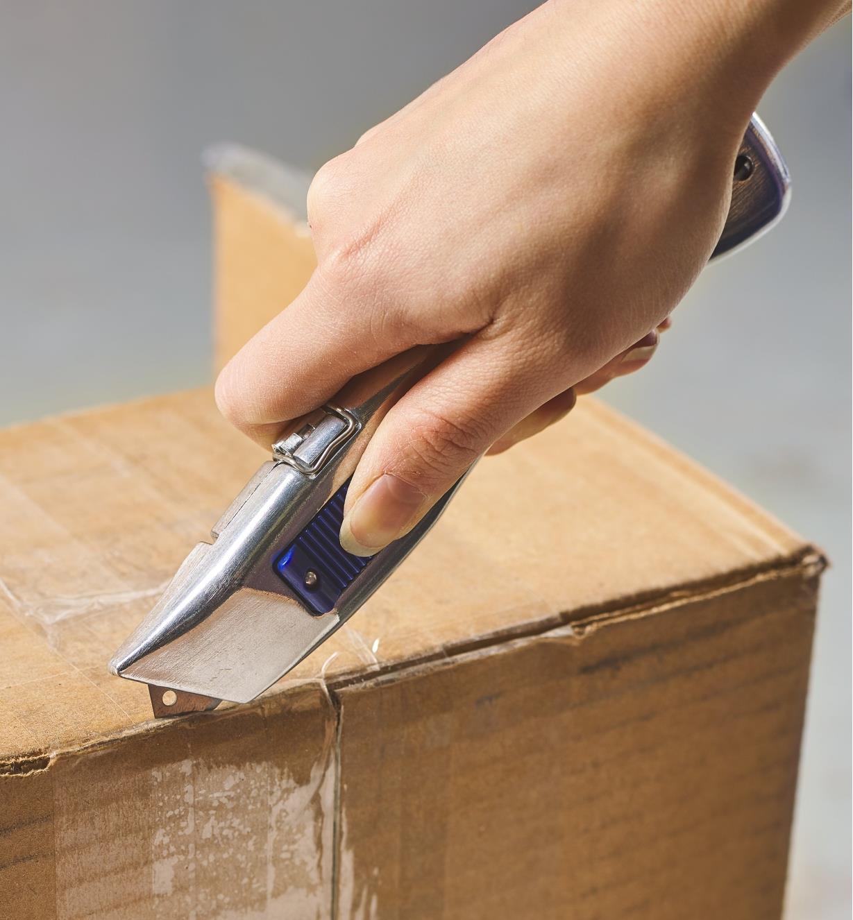 The Delphin 2013 retractable knife being used to cut open a taped box