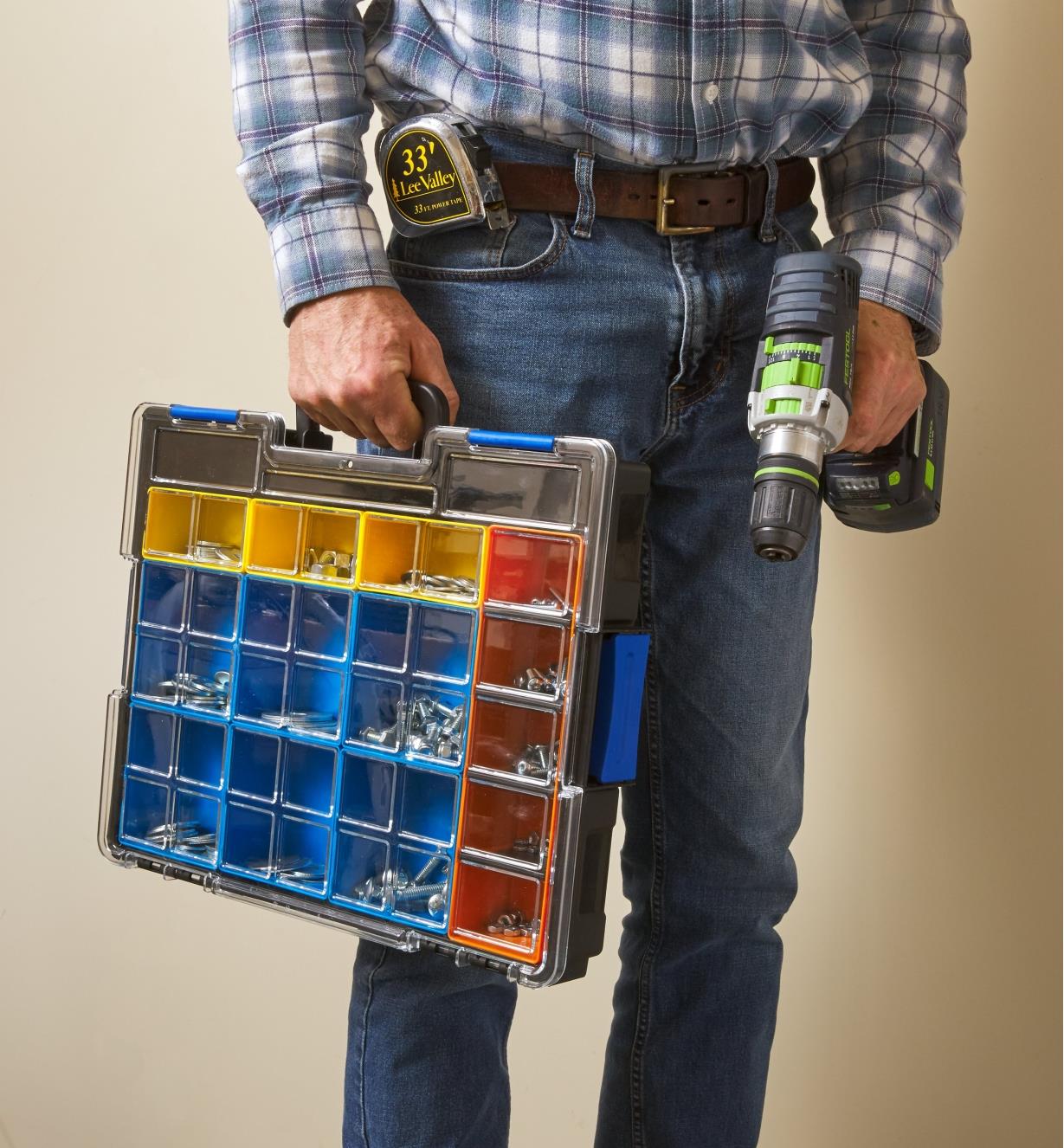 A man carries a drill and an Allit Pro 15-compartment case holding bins of nuts, bolts and washers
