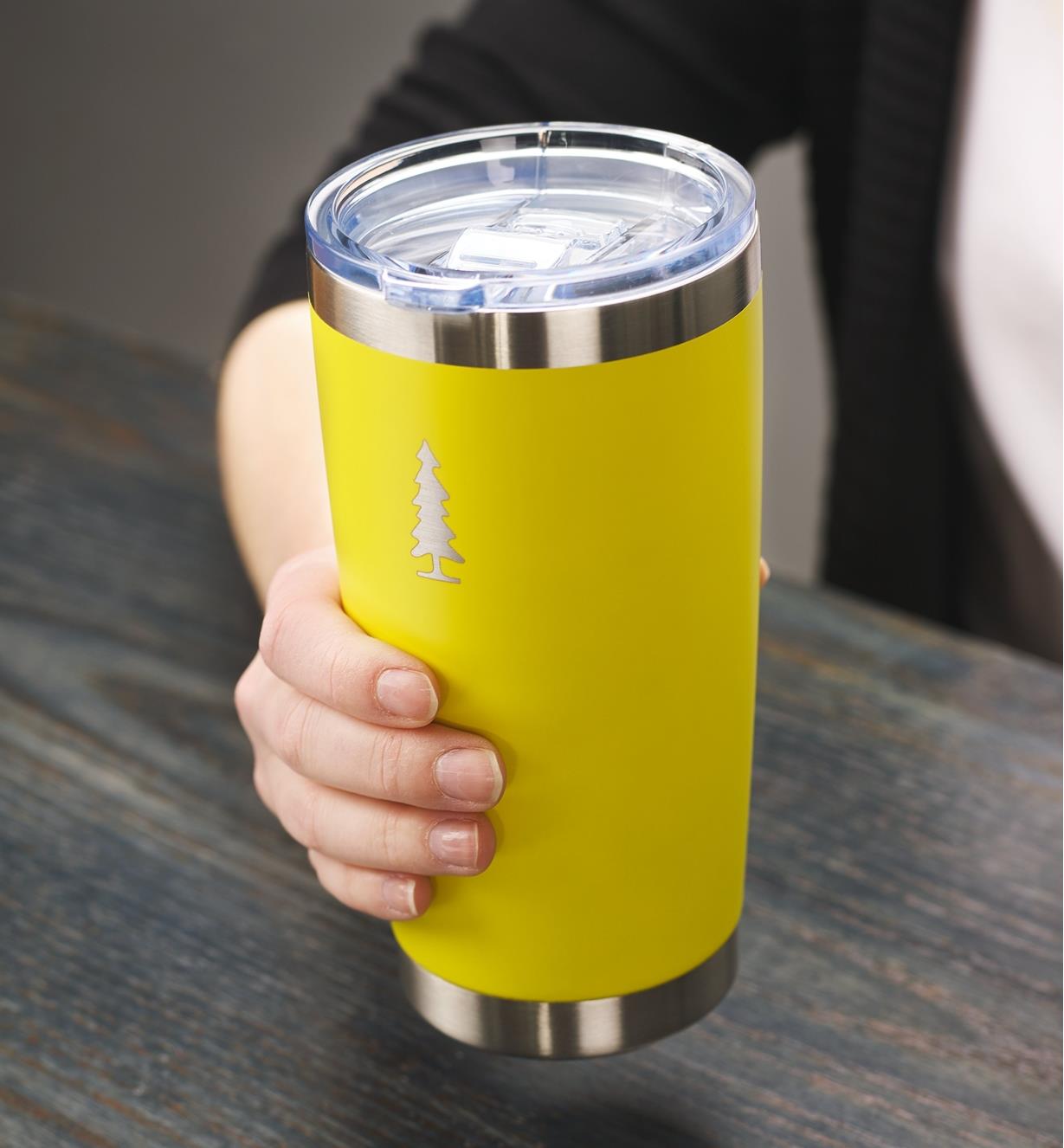 A woman holds a yellow 20 oz Lee Valley insulated tumbler
