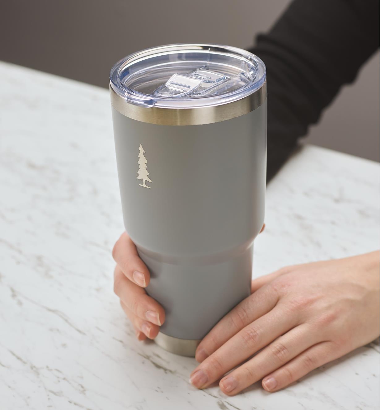 A woman holds a gray 30 oz Lee Valley insulated tumbler