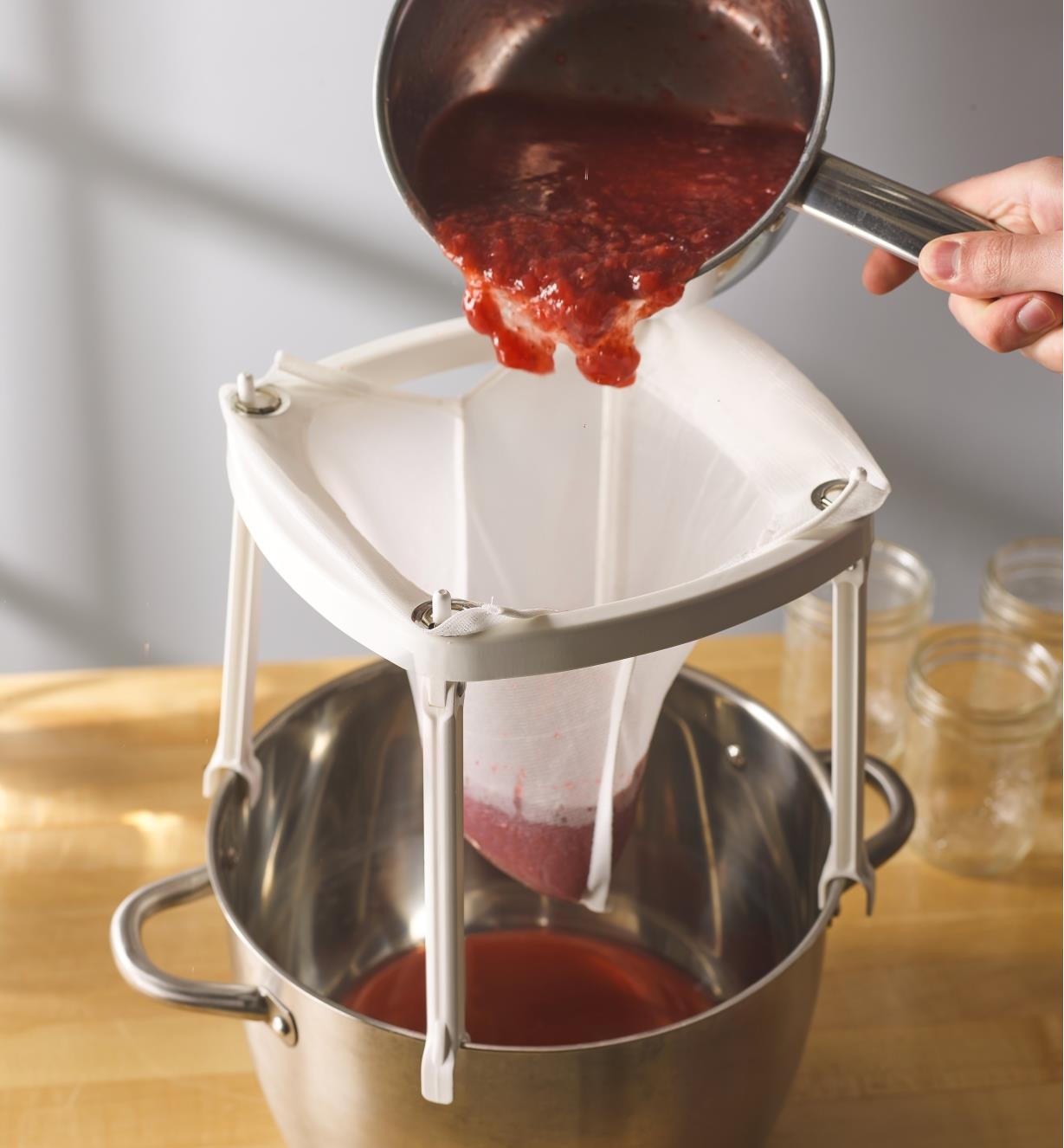 Pouring juices through a Jelly & Syrup Strainer sitting over a pot