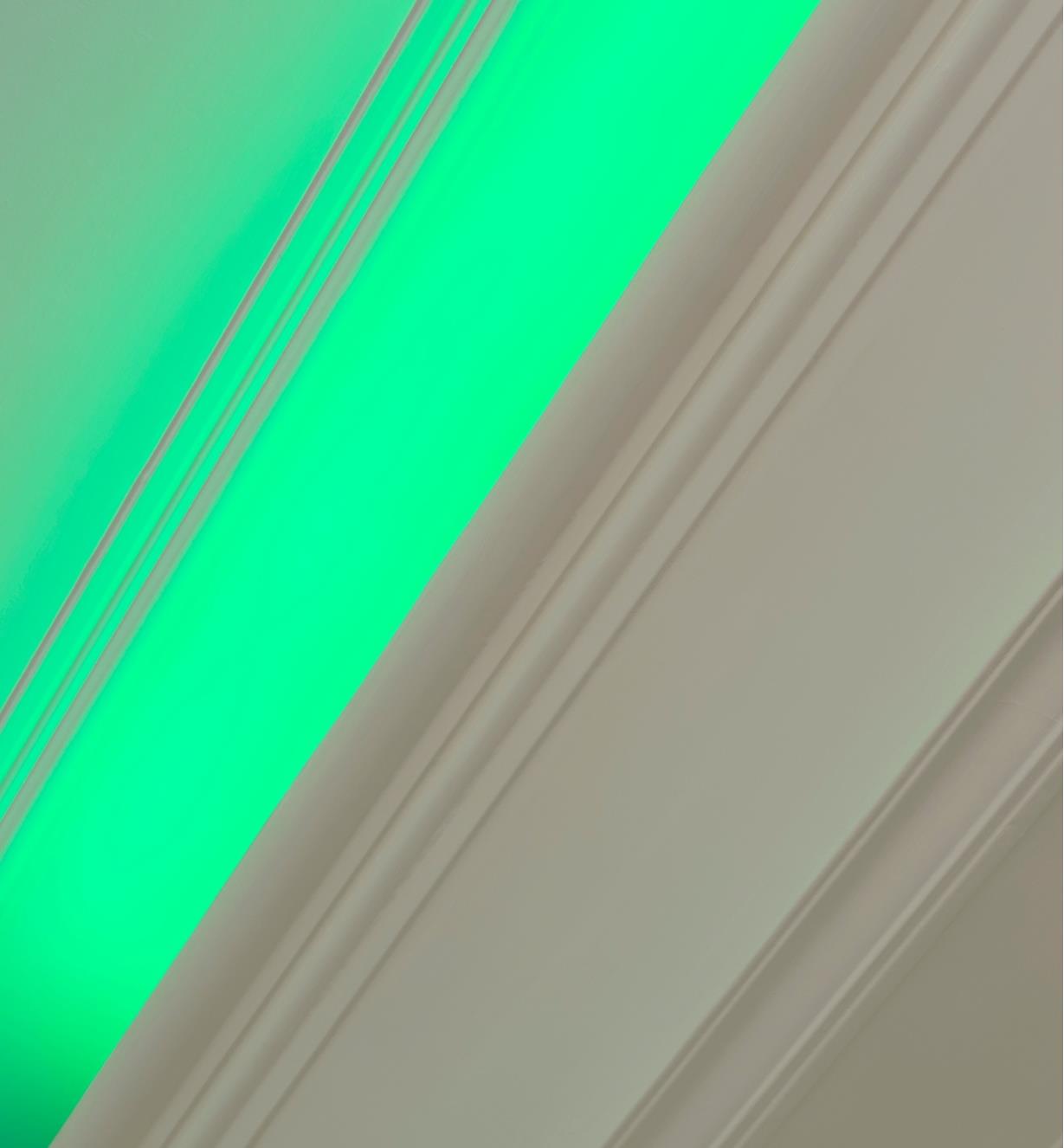 A section of crown molding casting a green glow on the ceiling