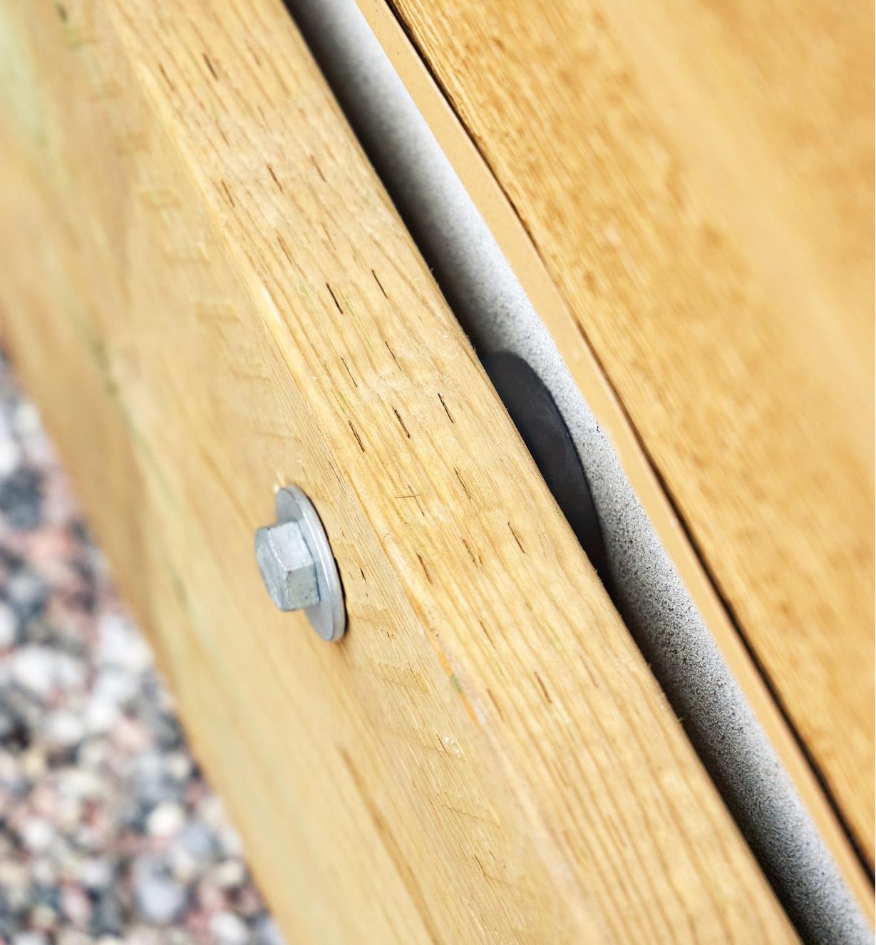 Close-up view of an installed deck-to-wall spacer between a ledger and a structure