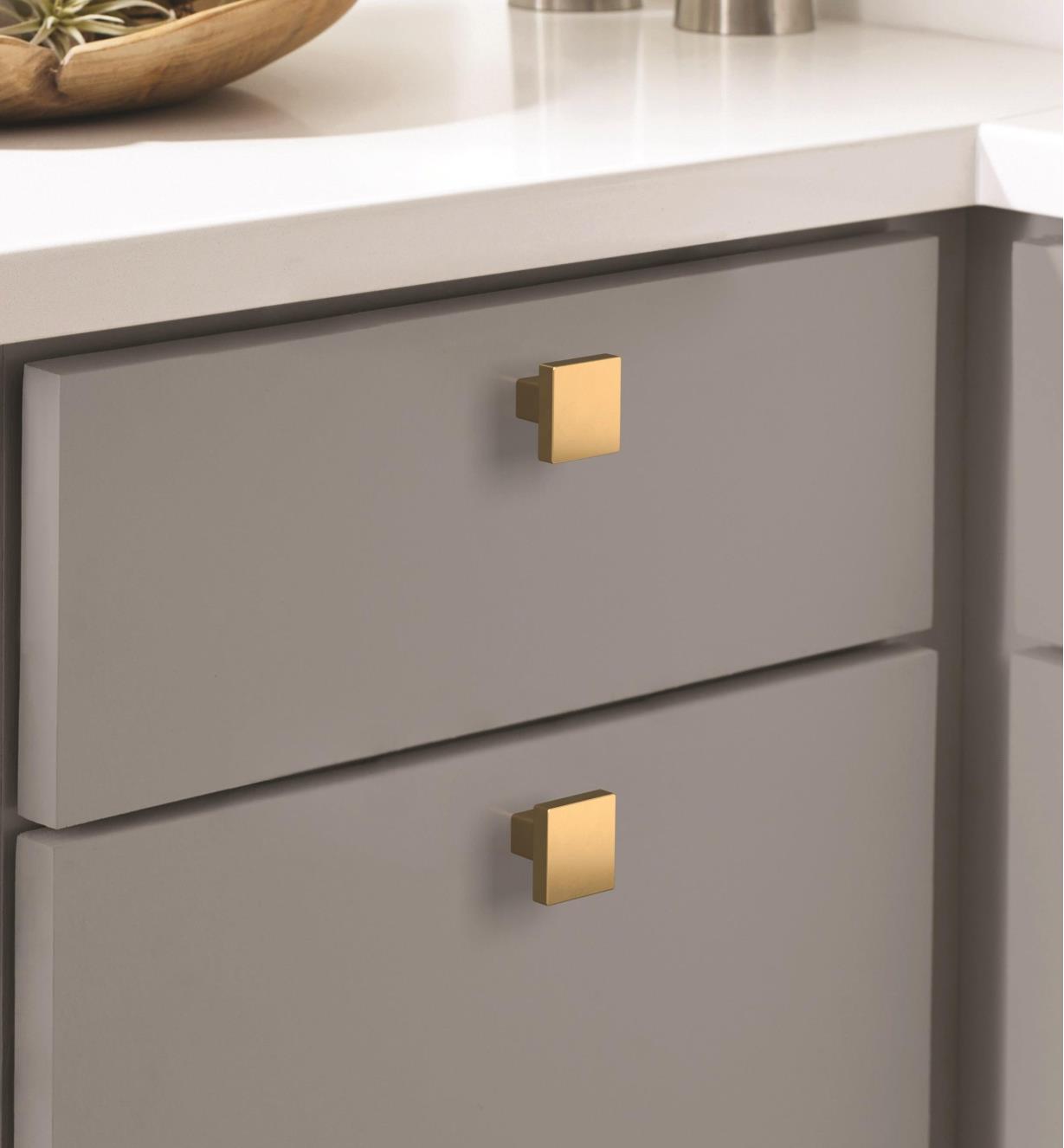 Two champagne bronze Monument square knobs mounted on two drawers