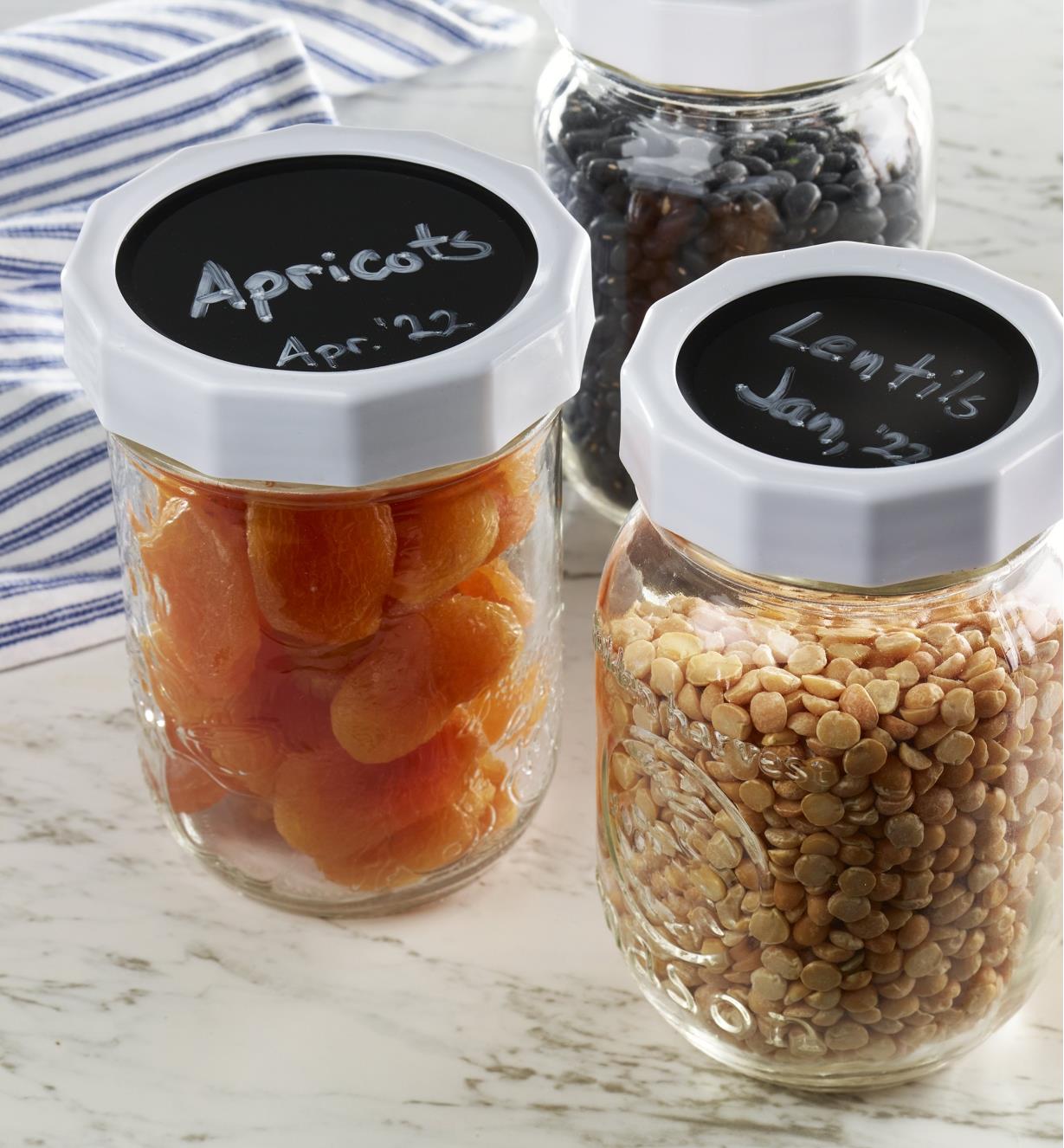 Repurposed canning jars filled with food items have labelled chalk top lids to identify contents