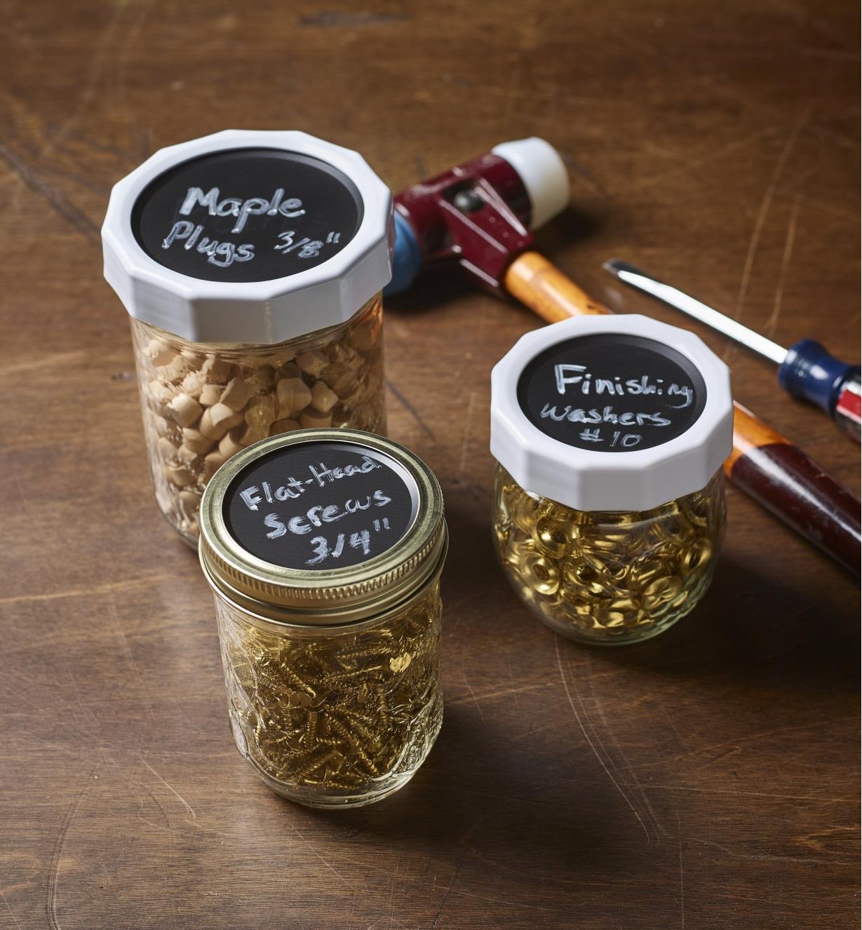 Repurposed canning jars filled with hardware and wood items have labelled chalk top lids to identify contents
