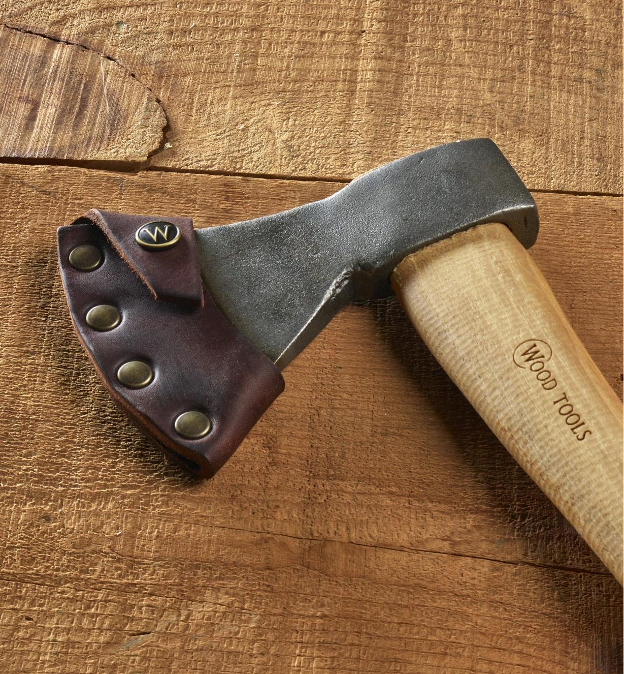 A carving axe with the leather sheath attached rests on a wood background