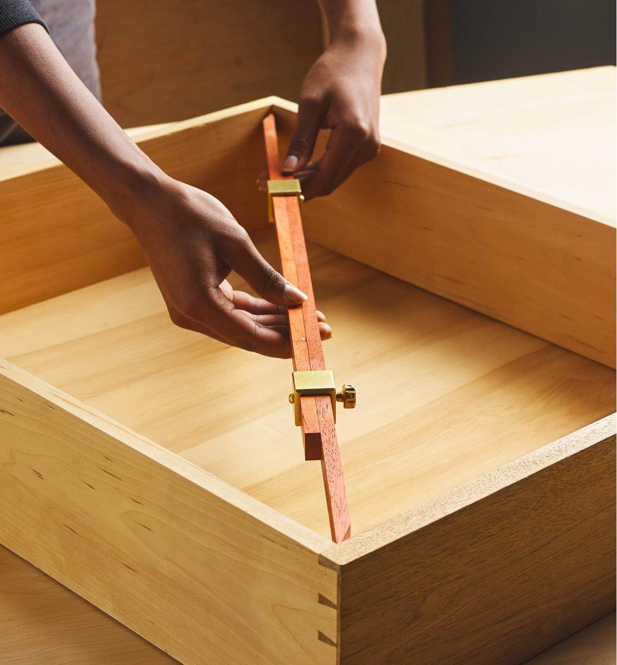 Personne utilisant une pige de mesure fabriquée avec les têtes Crucible pour relever une mesure intérieure d'un compartiment en bois
