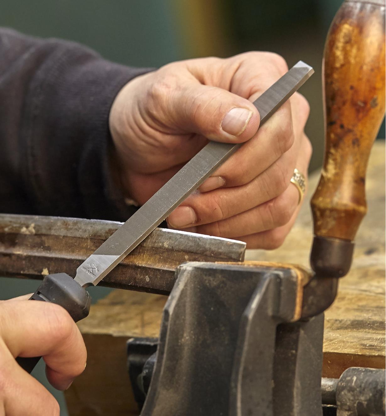 A woodworker uses a 6-inch mill bastard file to sharpen a drawknife