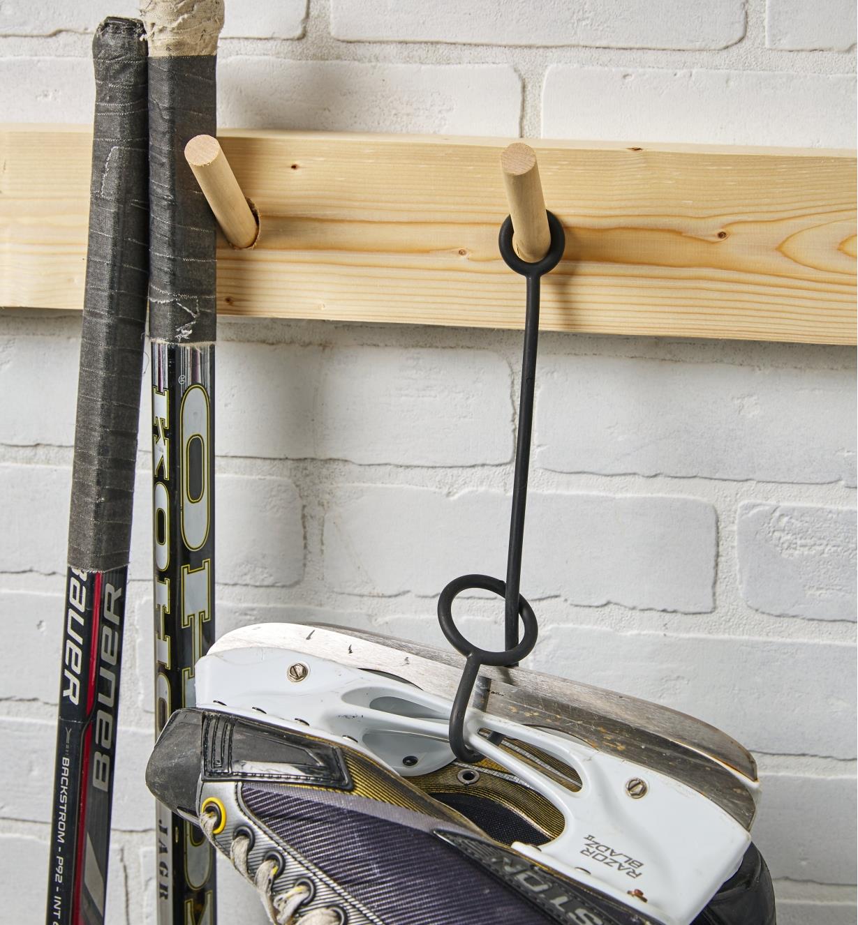 A KuVu strap holds a pair of hockey skates on a wall hook