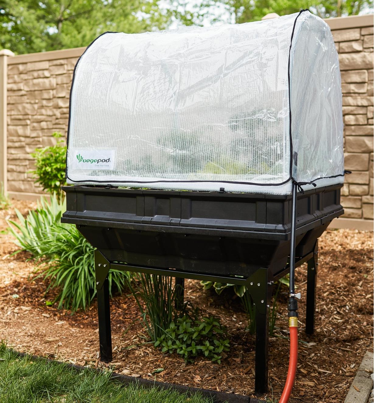 A Vegepod container garden with a base and the cover closed sits in a garden