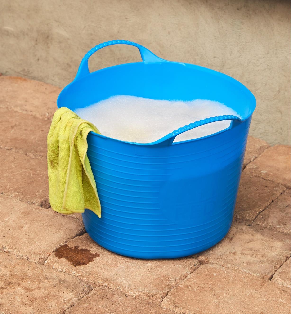 A 14 litre Tubtrug filled with soapy water, with a washcloth draped over the side