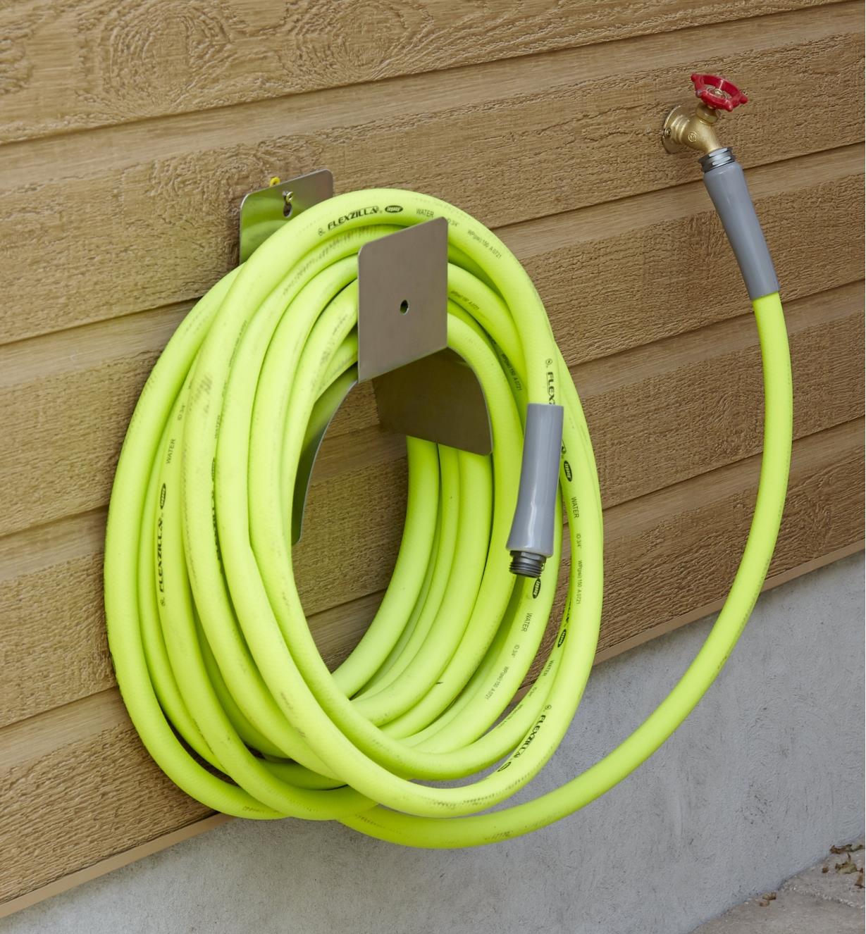 A 50' hose is coiled and hanging on an outdoor wall