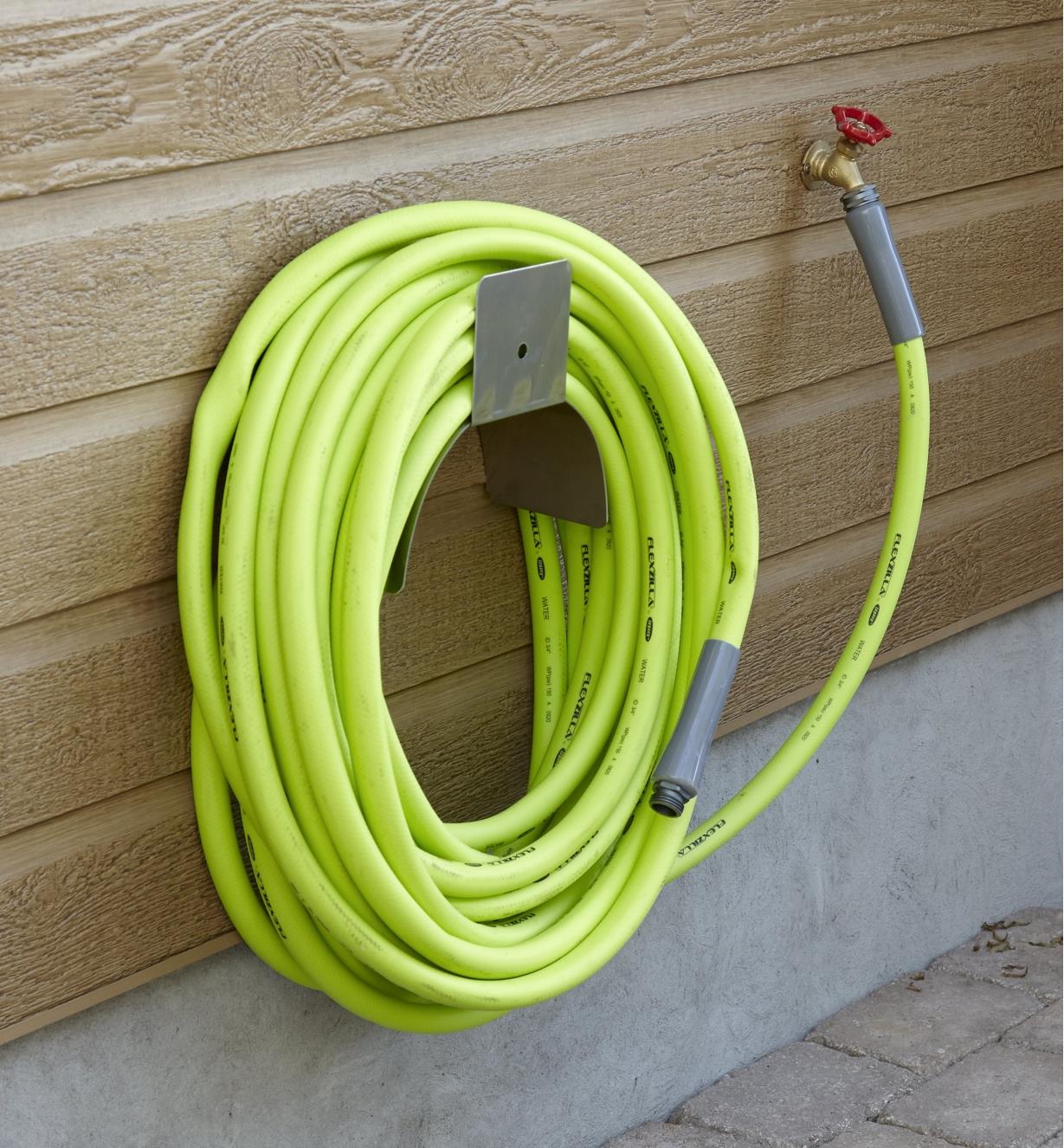 A 75' hose is coiled and hanging on an outdoor wall