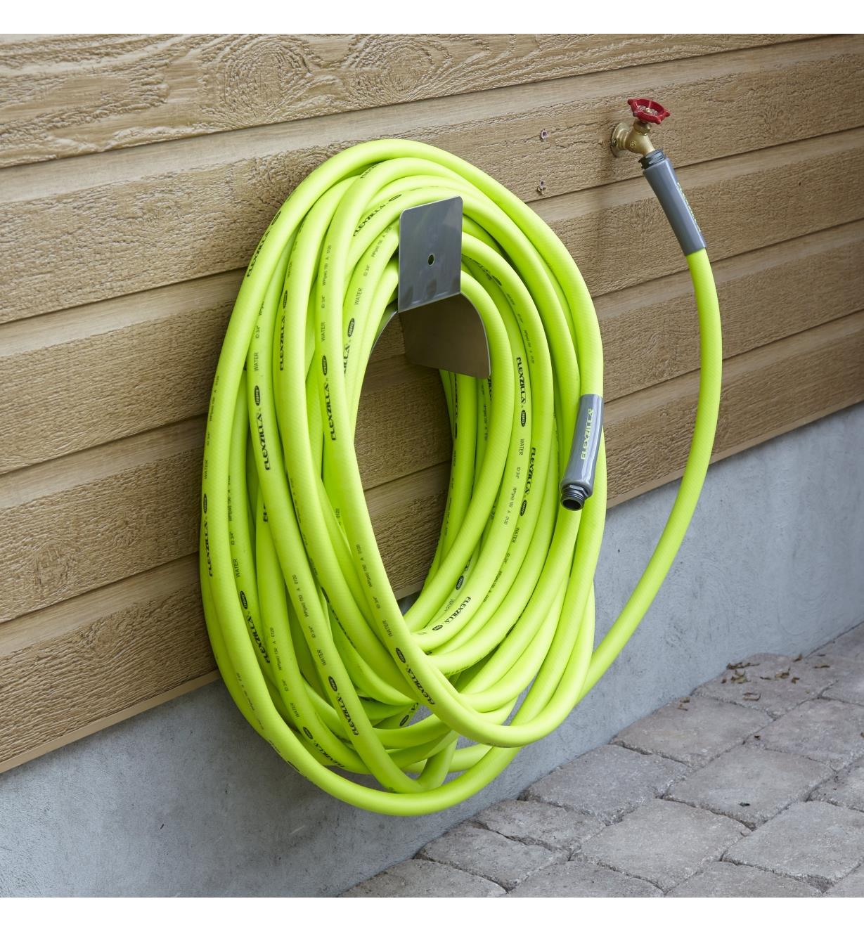 A 100' hose is coiled and hanging on an outdoor wall