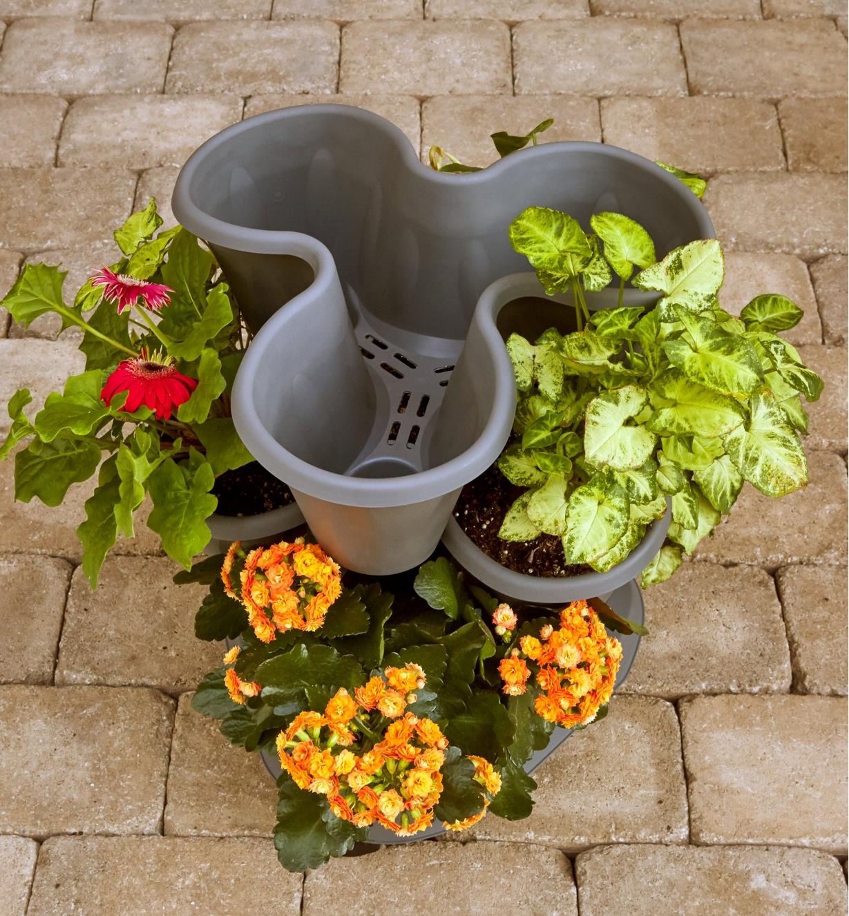 A triple planter with plants in the bottom two levels and the top level empty to show drainage ports