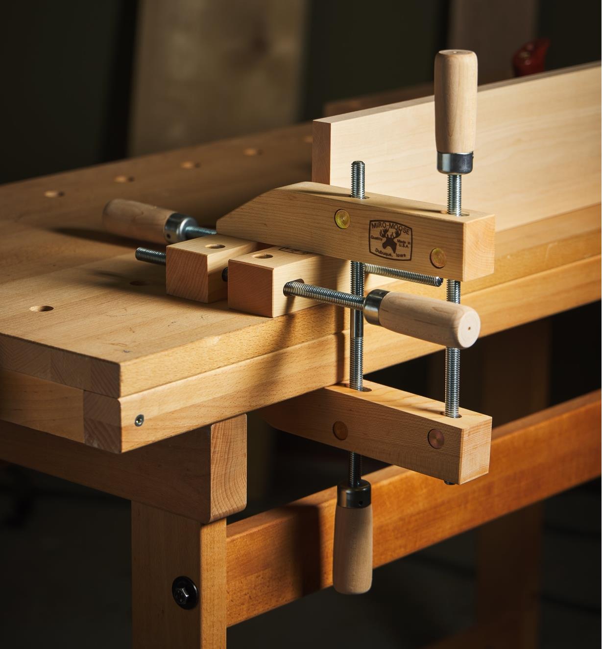 A wooden handscrew holding a workpiece on a workbench